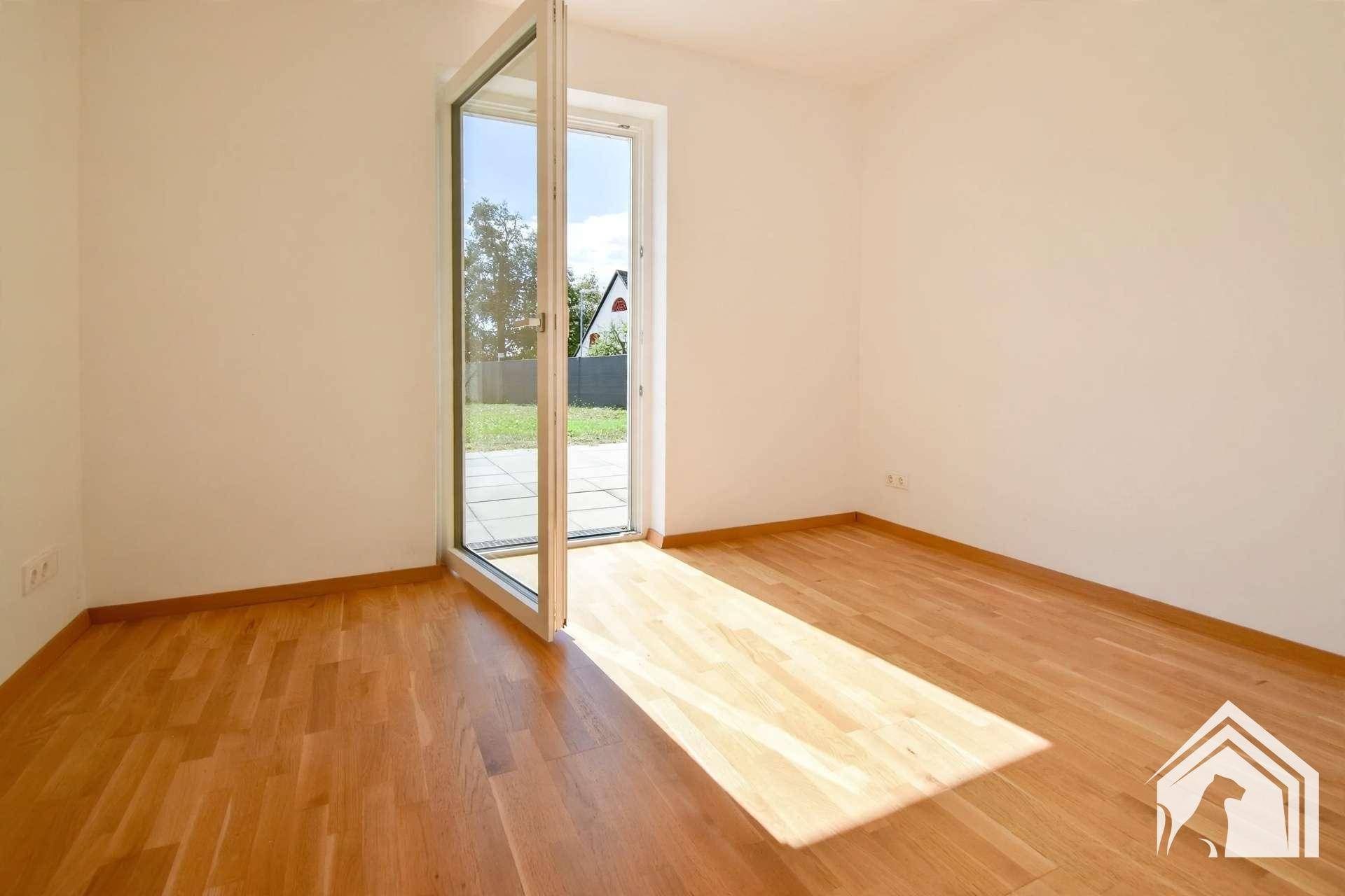 Lichtdurchflutetes Zimmer mit Holzboden und Ausgang zum Außenbereich, perfekt für viel Tageslicht.