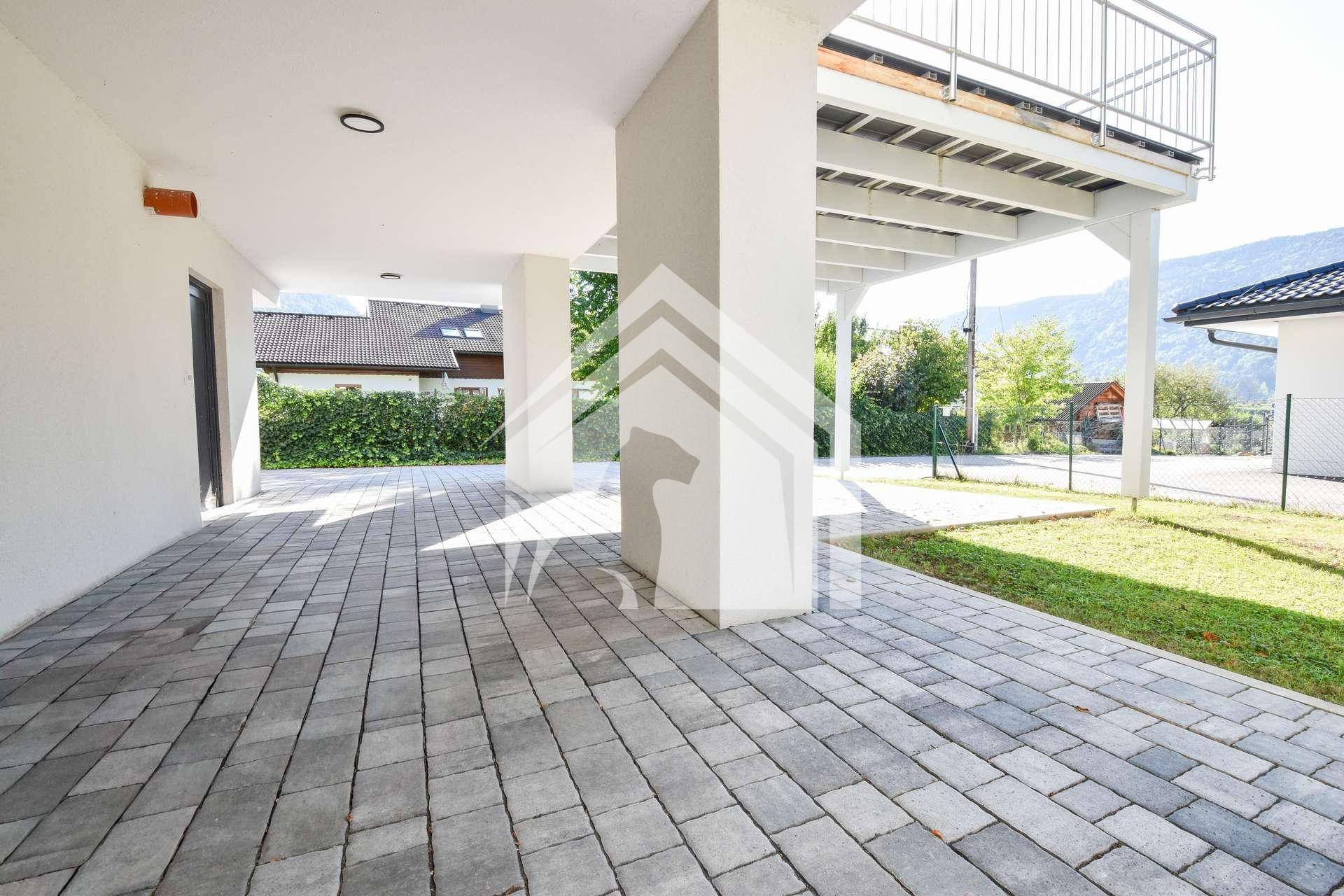 Geräumiger überdachter Bereich mit gepflastertem Boden unter dem Balkon, bietet Schutz.