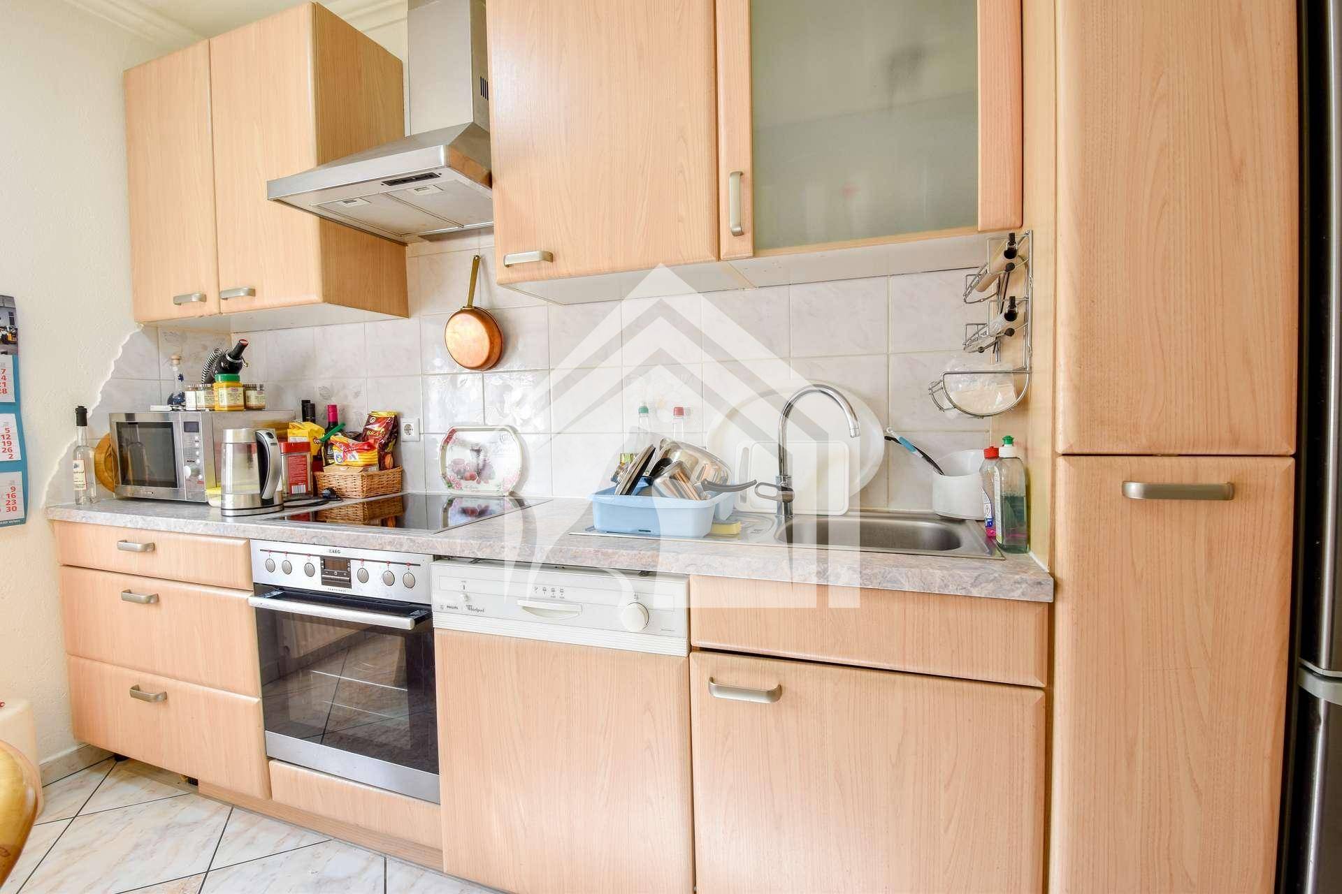 Einbauküche mit hellen Holzschränken, integrierten Geräten und Fliesenrückwand.