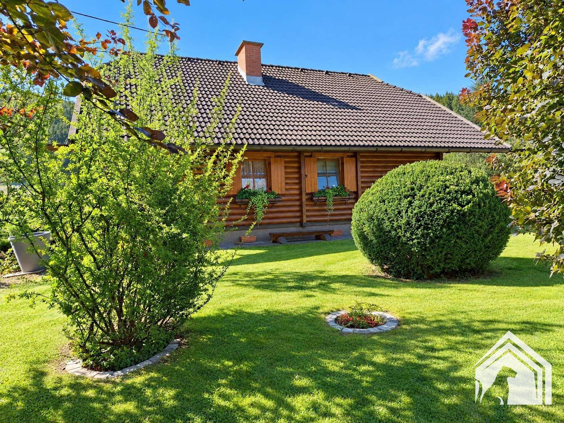 Idyllischer Gartenbereich mit gepflegtem Rasen und Sträuchern neben dem Holzhaus.