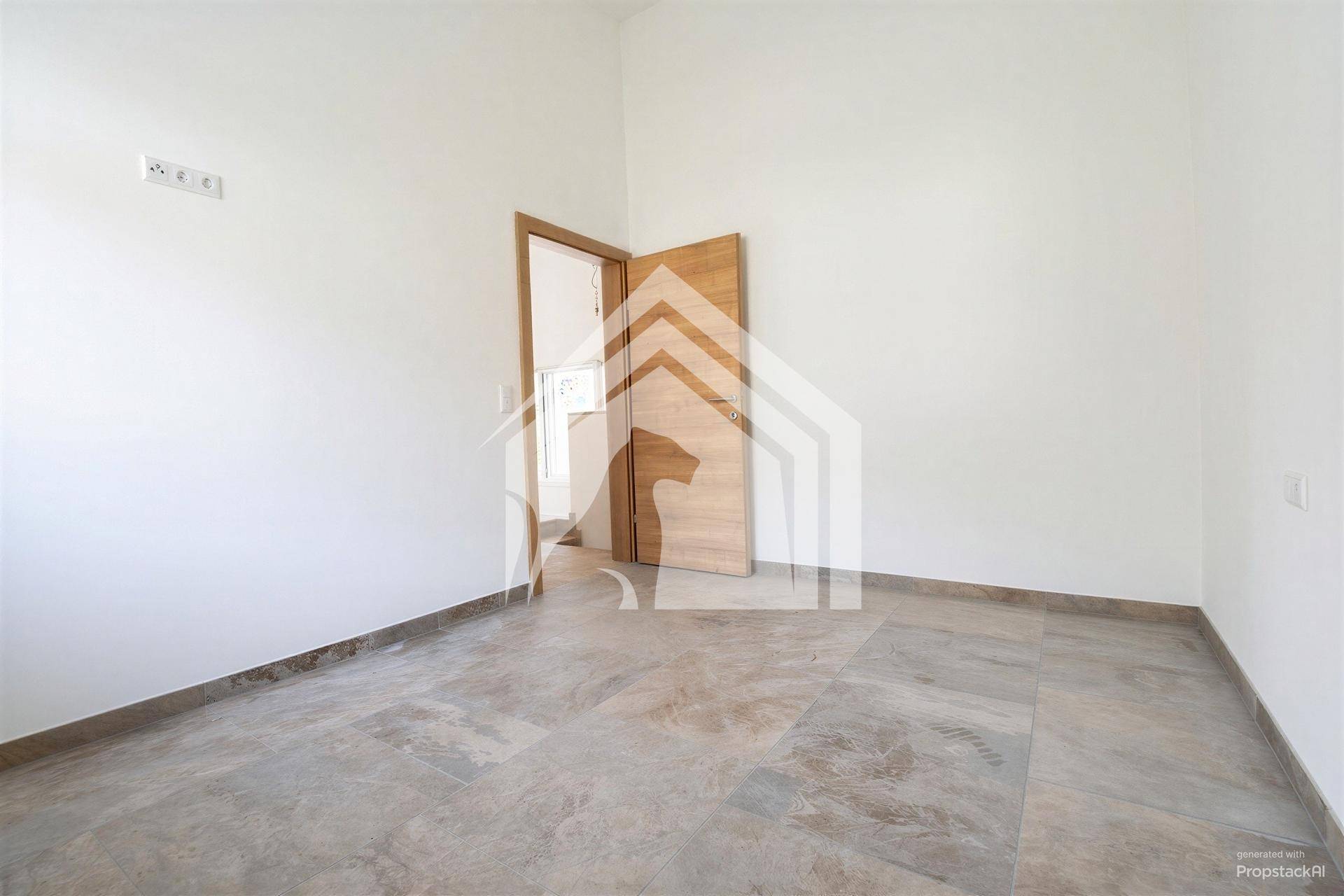 Leeres Zimmer mit Fliesenboden, Holztür und viel natürlichem Lichteinfall.