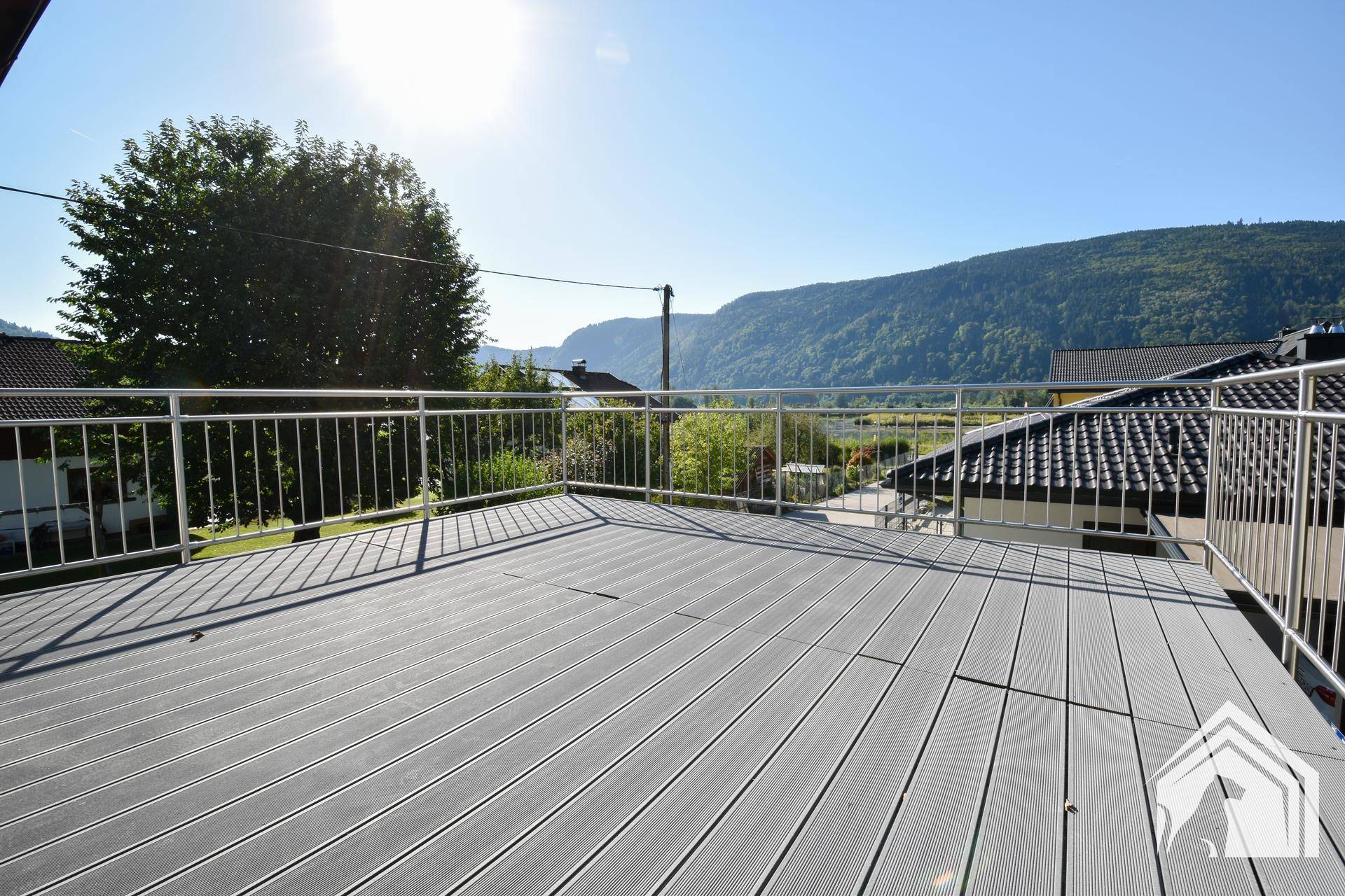 Geräumige Terrasse mit Holzdielen und Metallgeländer bietet weiten Blick auf die Berge.