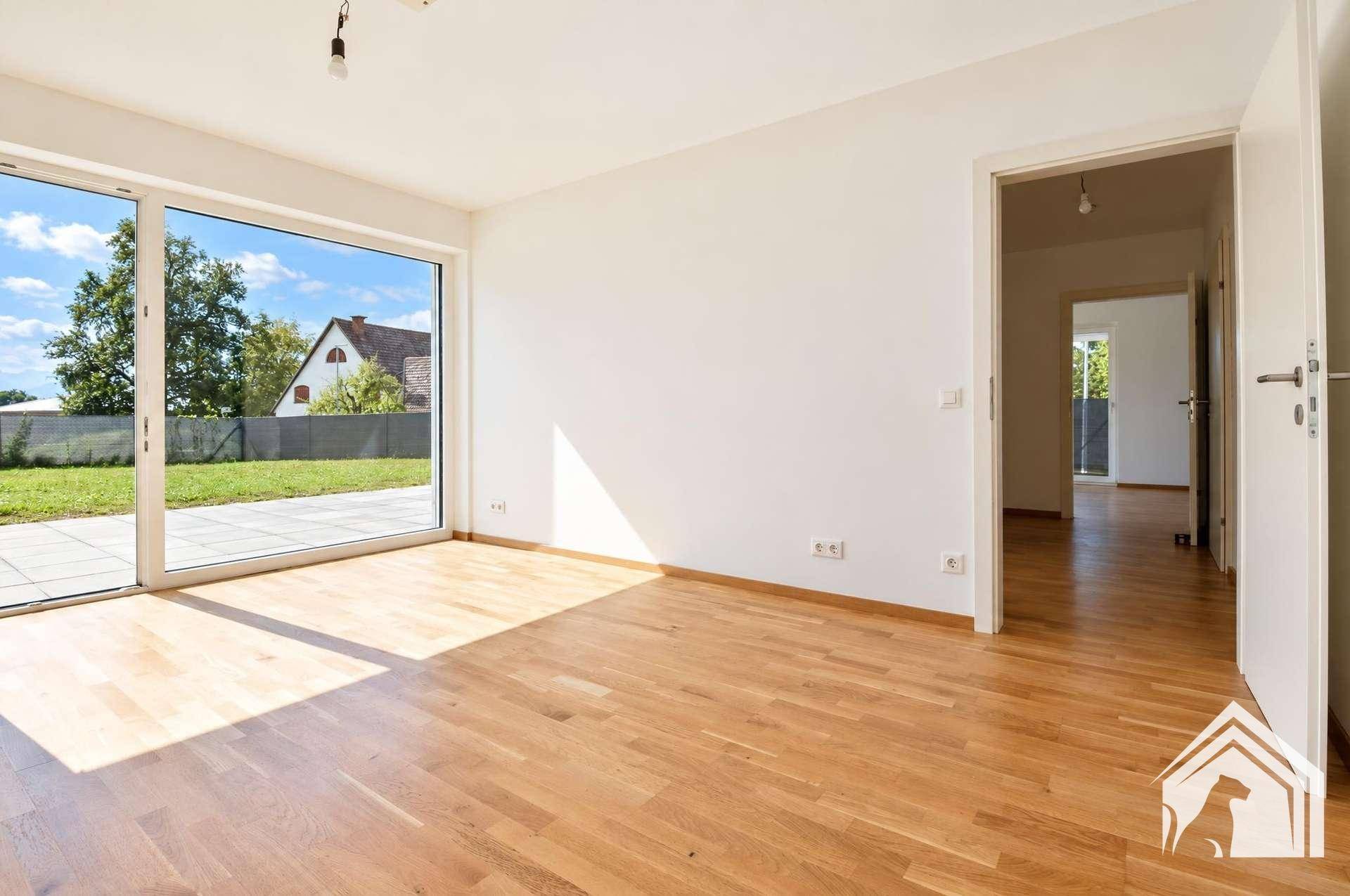 Helles Wohnzimmer mit Parkettboden und großzügigem Zugang zur Terrasse und Garten.