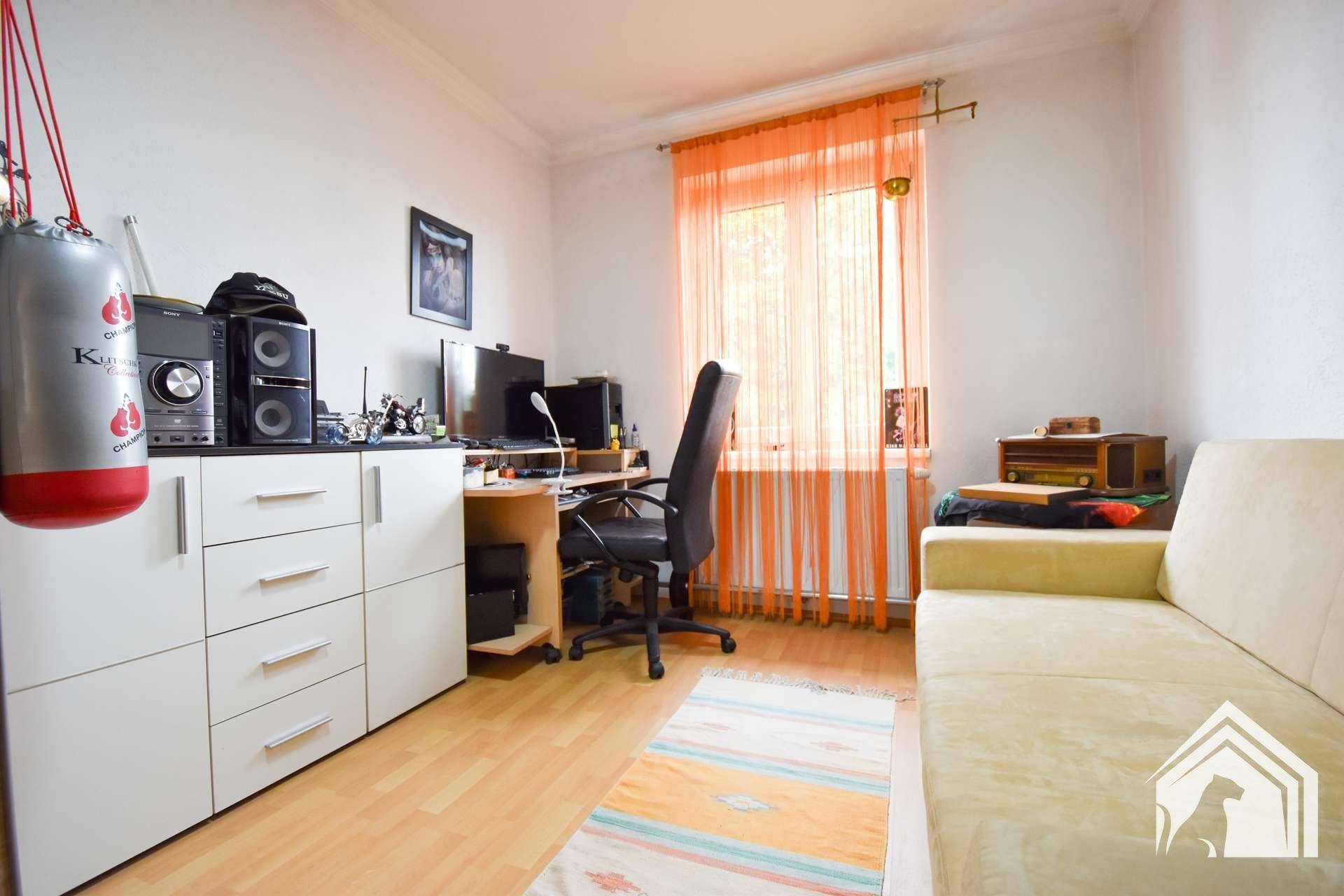 Helles Arbeitszimmer mit Schreibtisch, Stauraum und einem Sofa, ideal für Home-Office.