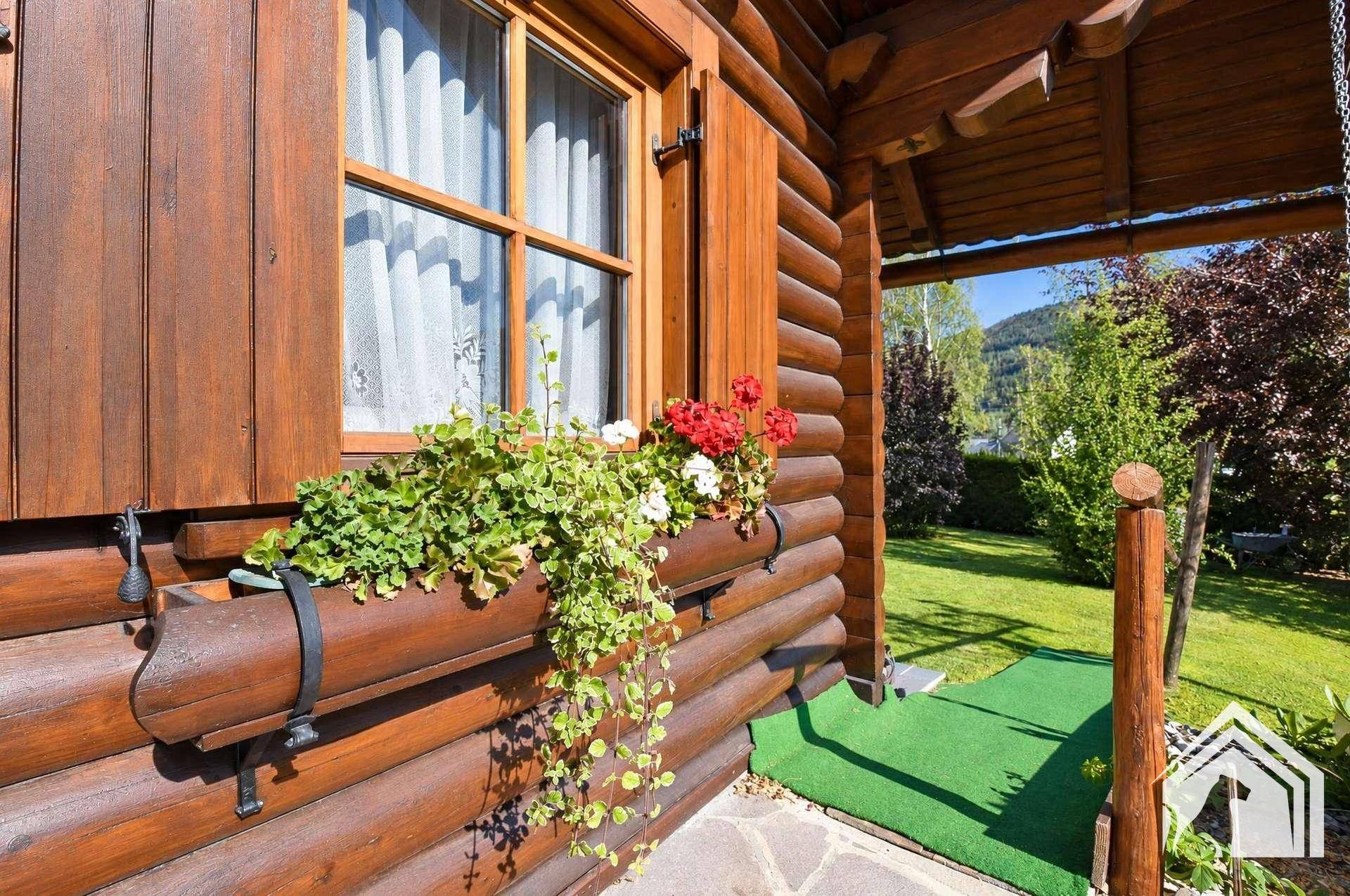 Detailansicht eines Fensters mit Blumenkästen an der Holzfassade des Hauses.