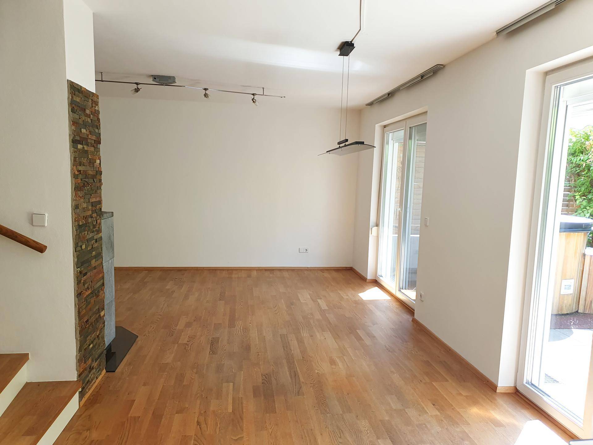 Helles Wohnzimmer mit Holzboden, dekorativer Steinwand und Zugang zur Terrasse.