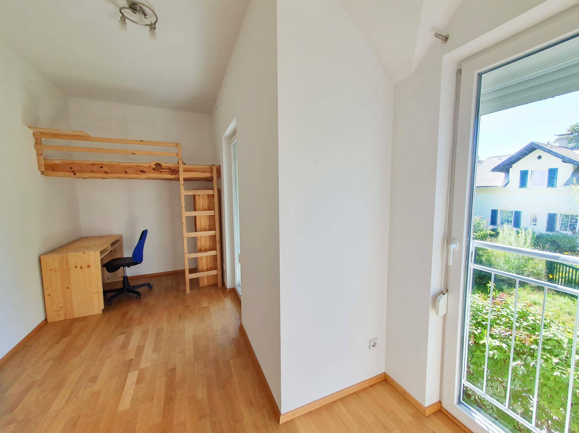 Helles Kinderzimmer mit Hochbett, Schreibtisch und Balkonzugang mit Blick auf die Nachbarschaft.