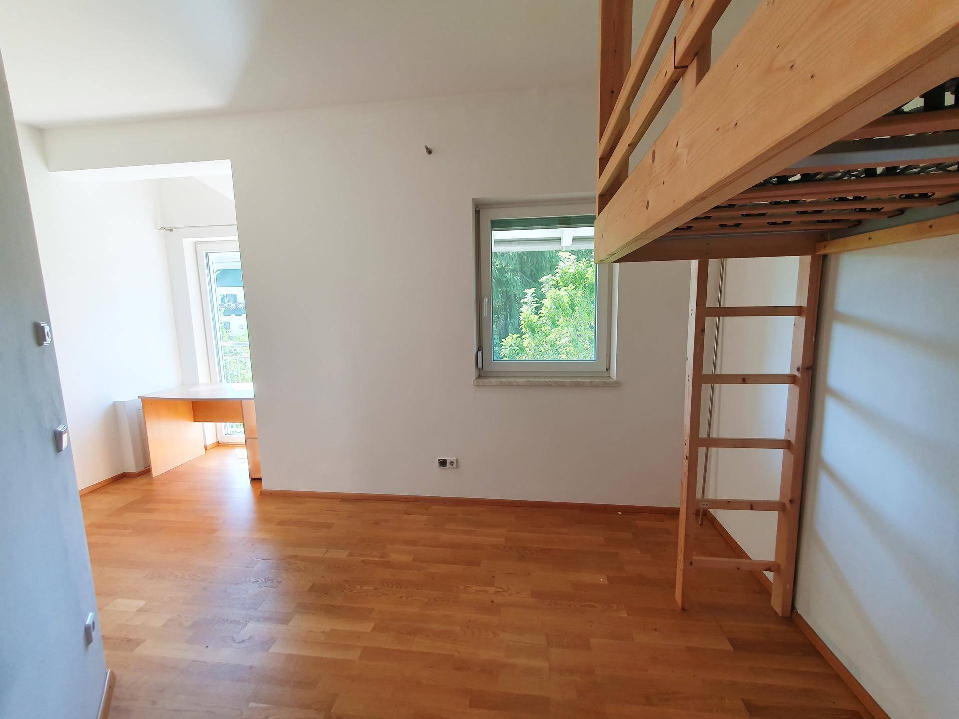 Kinderzimmer mit Hochbett, Schreibtisch und Blick ins Grüne durch das Fenster.