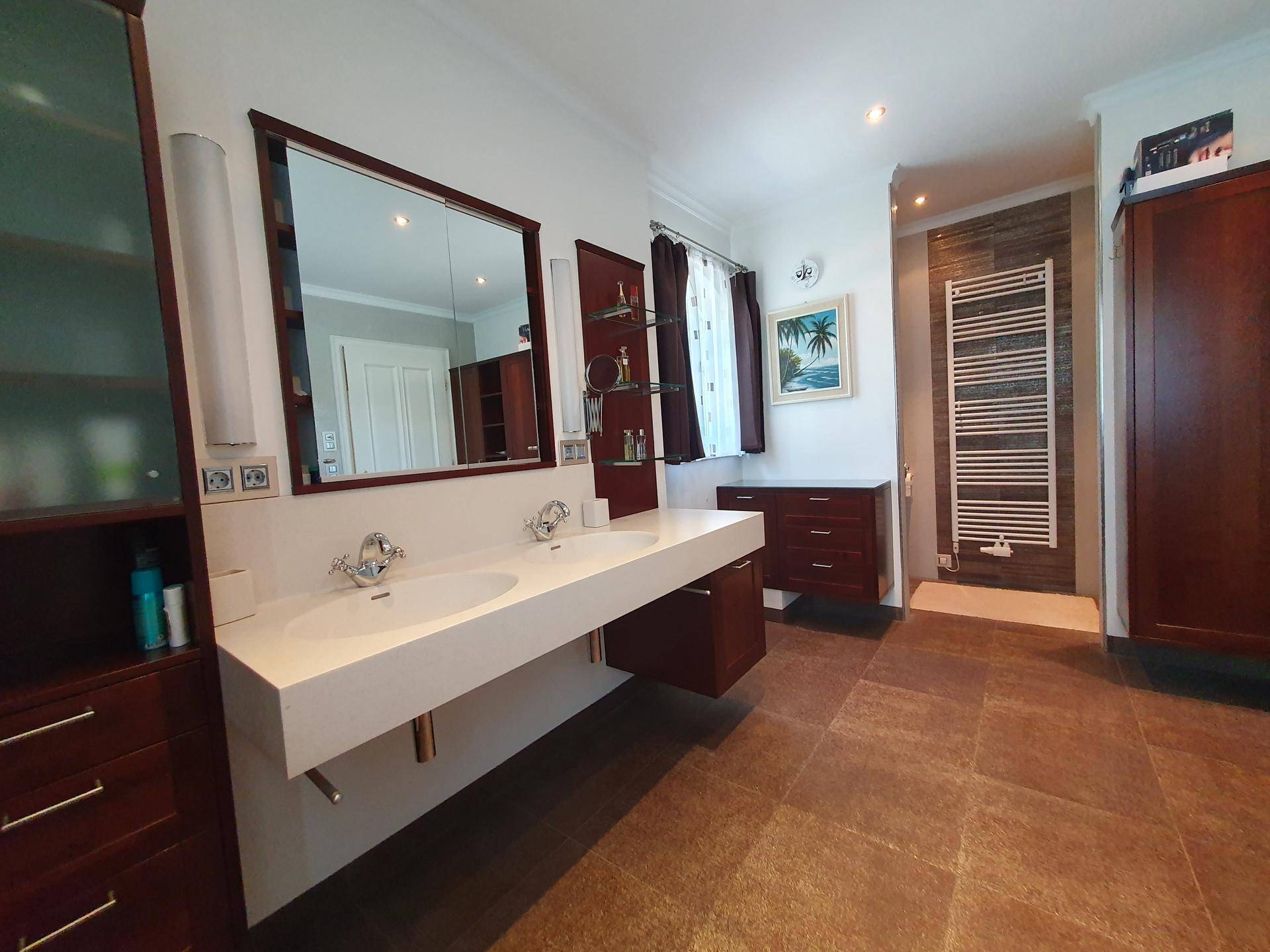 Modernes Badezimmer mit Doppelwaschbecken, großem Spiegel und beheiztem Handtuchhalter.