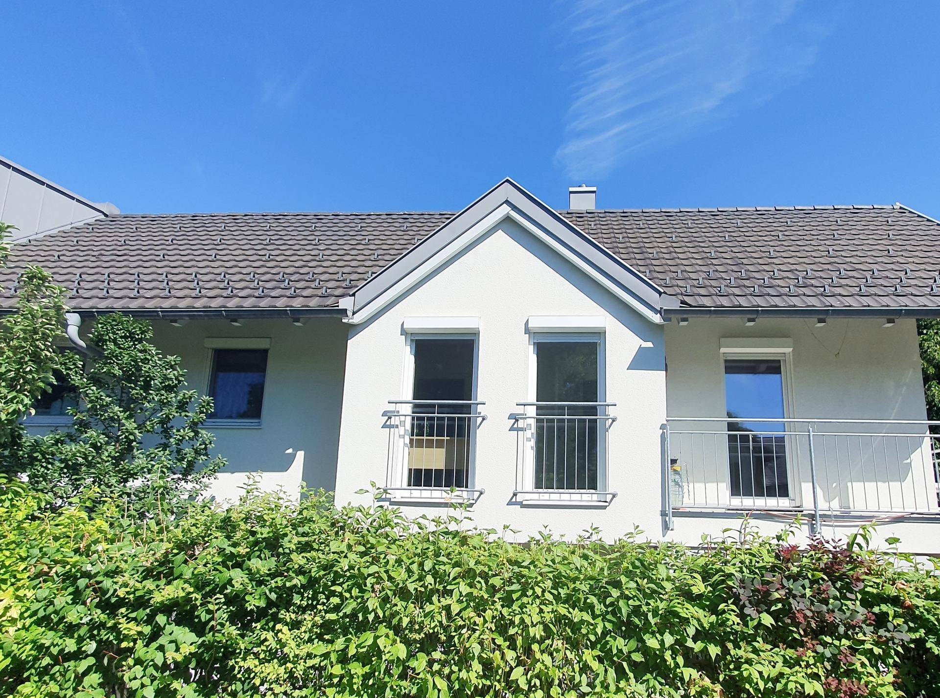 Rückansicht des Hauses mit Satteldach, französischen Balkonen und grüner Umgebung.