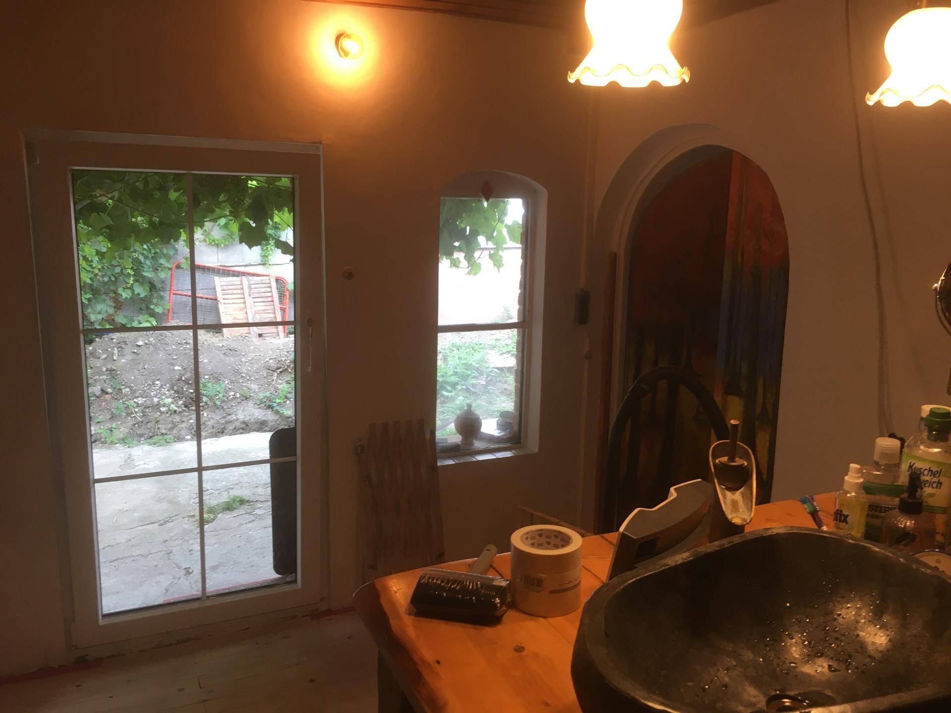 Raum mit Waschbecken und Blick in den Garten, einfach eingerichtet.