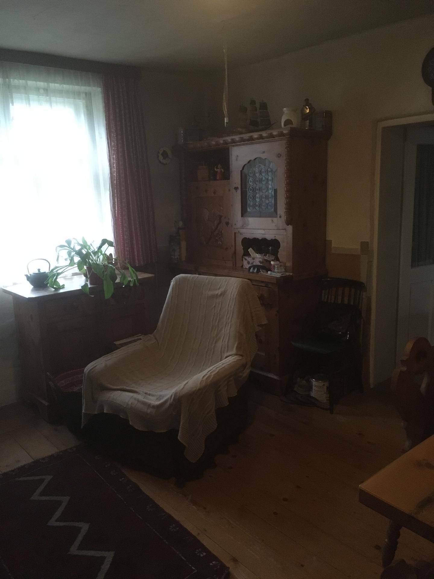Traditionell eingerichtete Stube mit Holzmöbeln und Fenster, gemütliche Atmosphäre.
