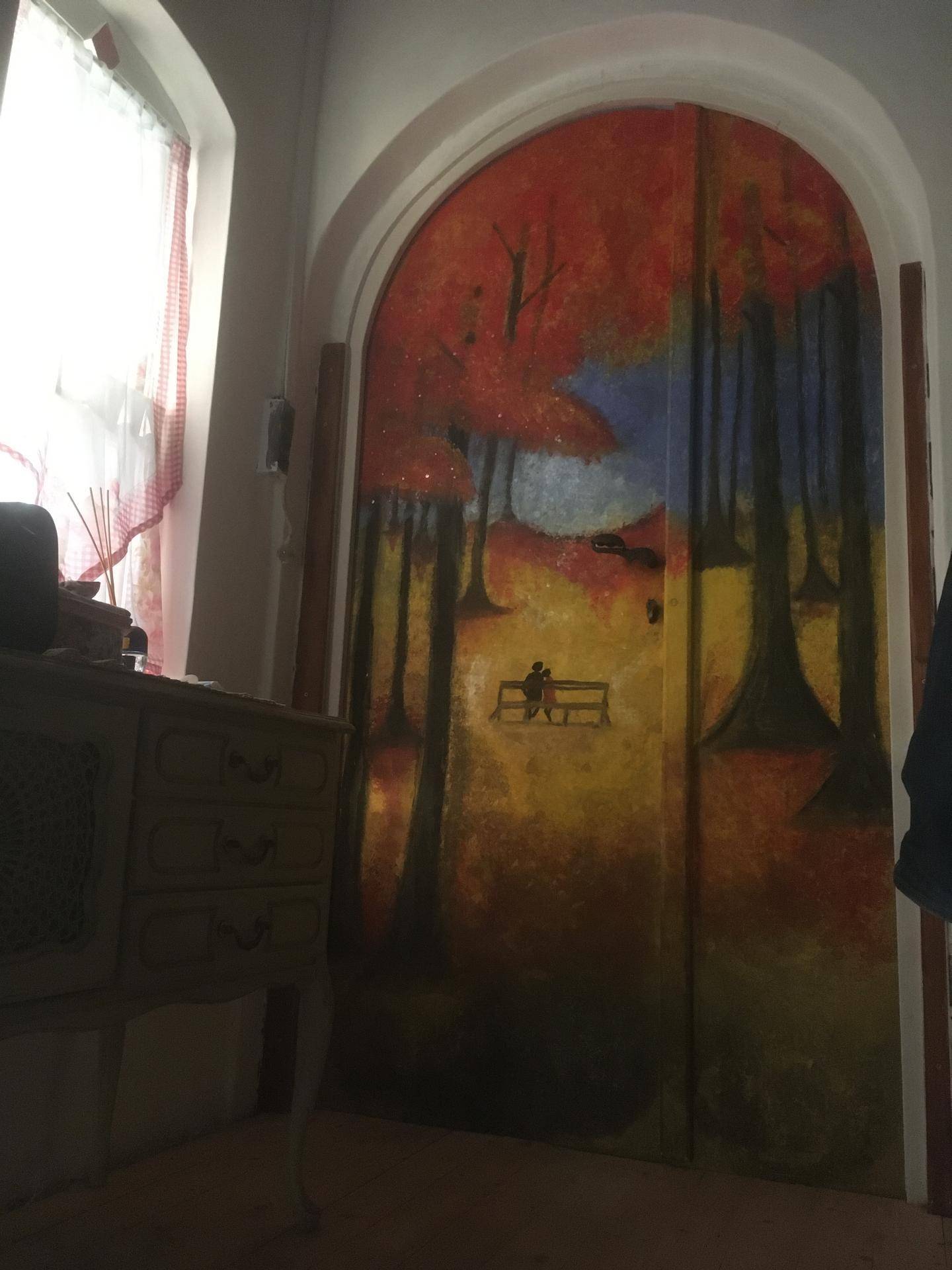 Farbenfroh bemalte Tür mit Herbstmotiv in einem gewölbten Durchgang.