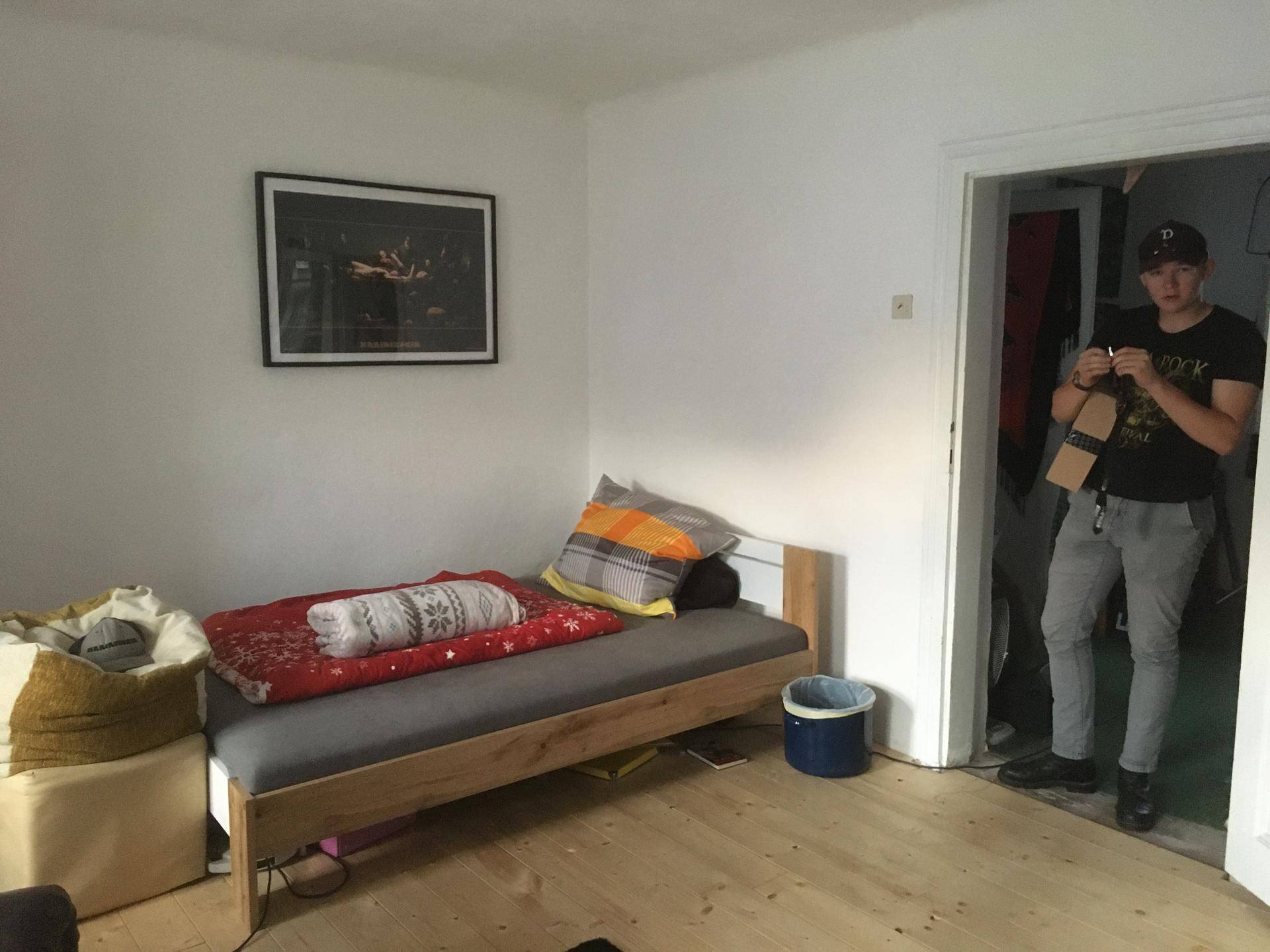 Schlafzimmer mit Einzelbett, Holzboden und Blick in den Nebenraum.
