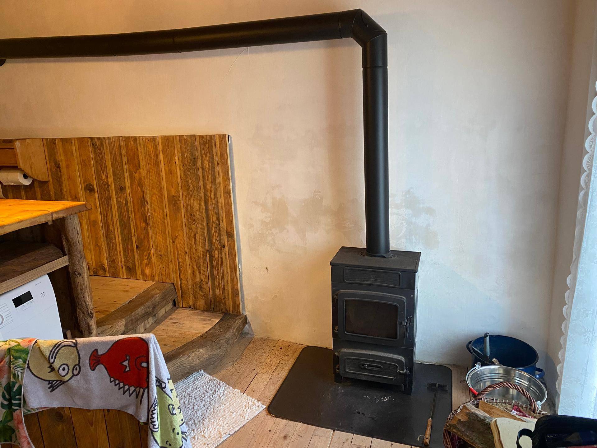 Hauswirtschaftsraum mit Kaminofen, Waschmaschine und Holzverkleidung.
