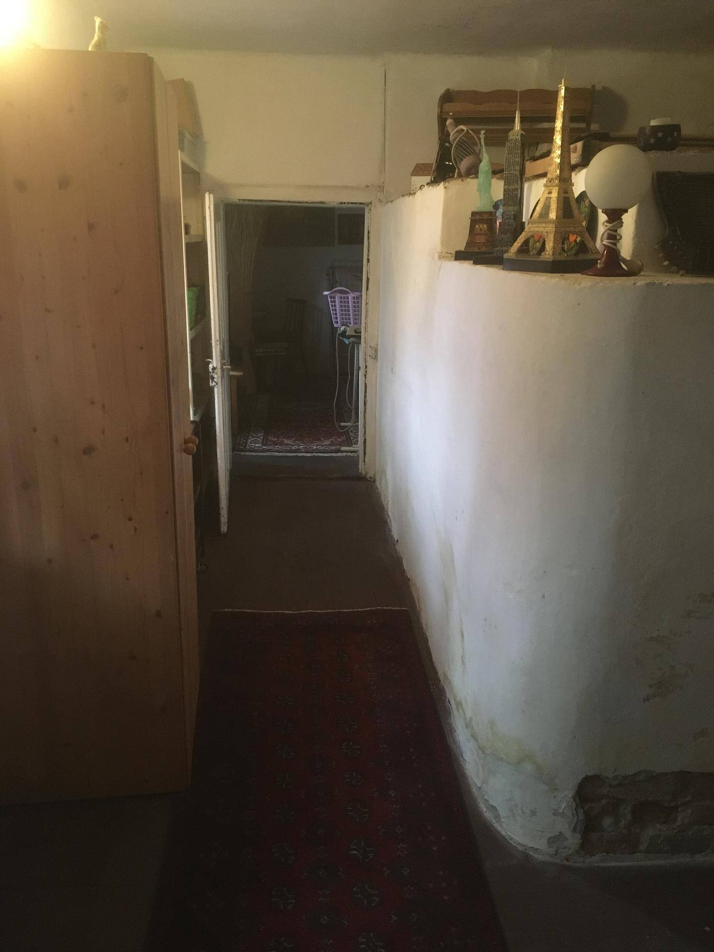 Langer Flur mit Teppich und Blick in den nächsten Raum, schlicht gehalten.