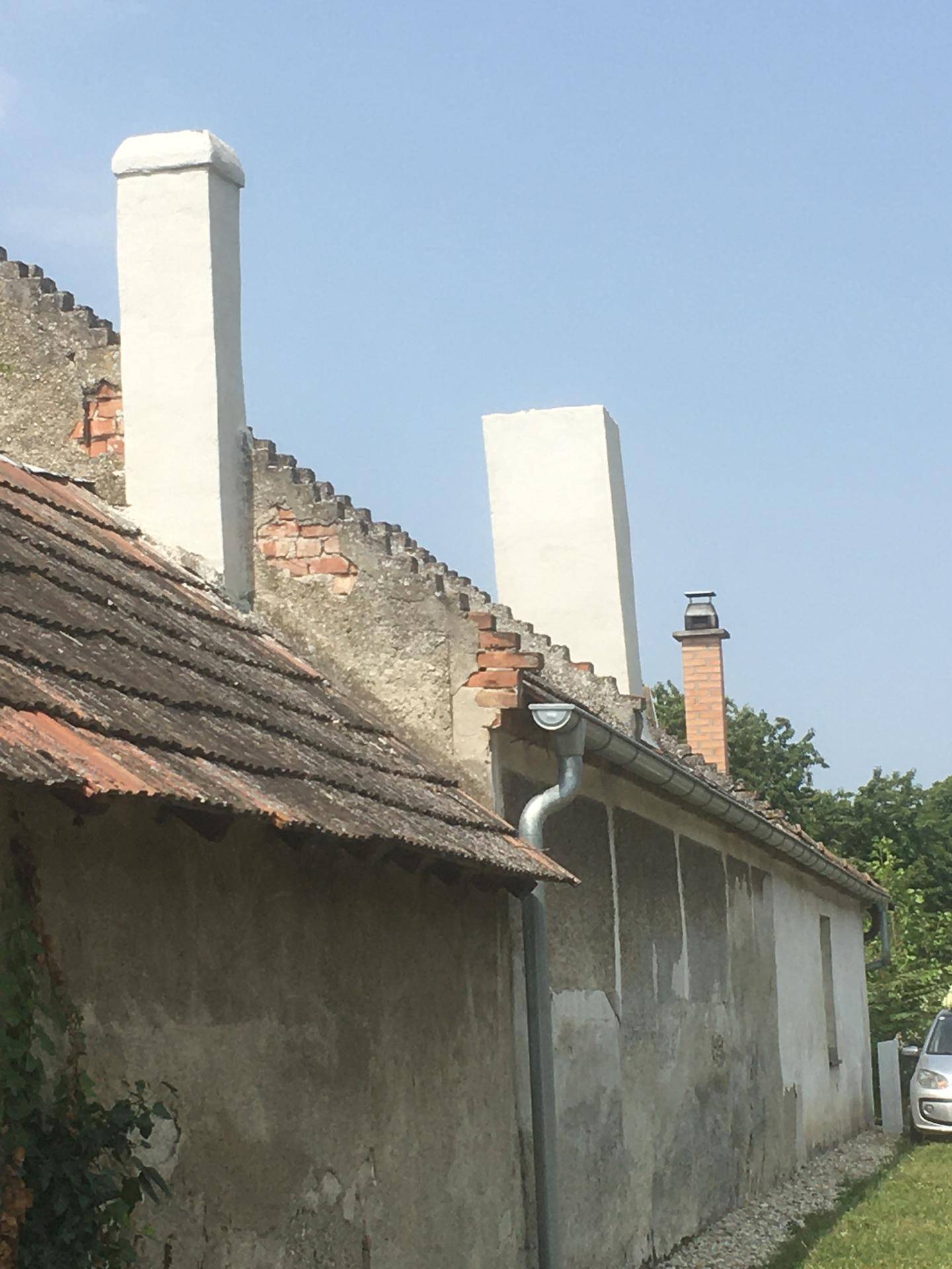 Nahaufnahme des alten Ziegeldachs und der verschiedenen Schornsteine eines Landhauses.