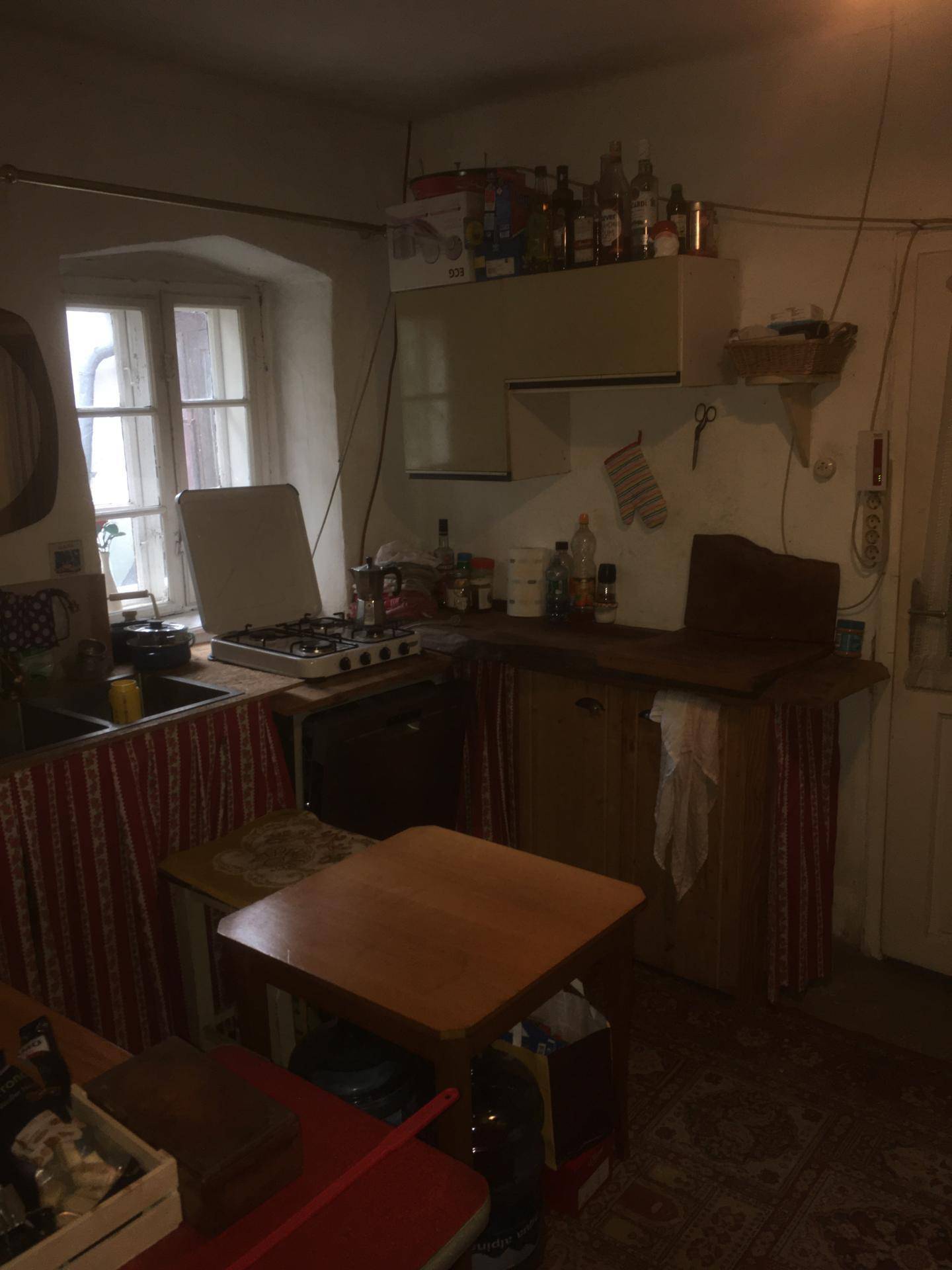 Küche mit Gasherd, Spülbecken und Fenster, einfach und funktional eingerichtet.