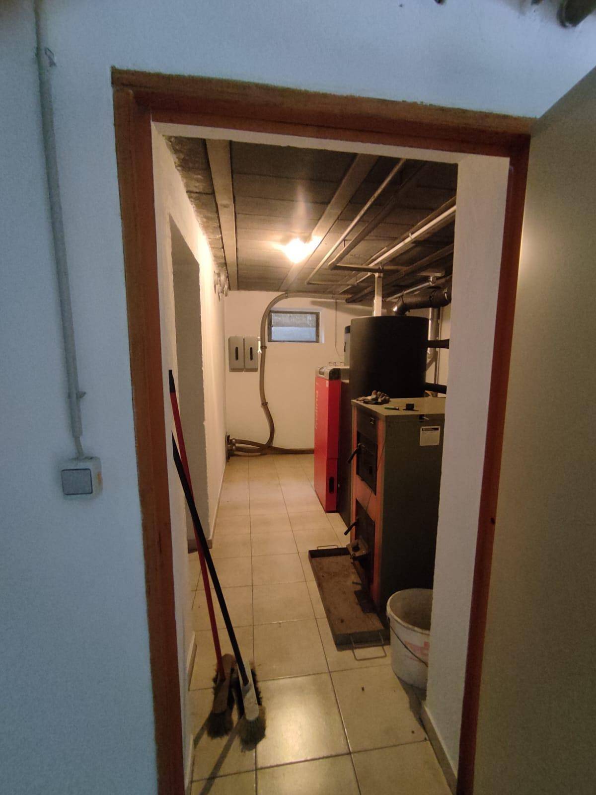 Heizungsraum im Keller mit Fliesenboden und sichtbaren Heizungsanlagen.