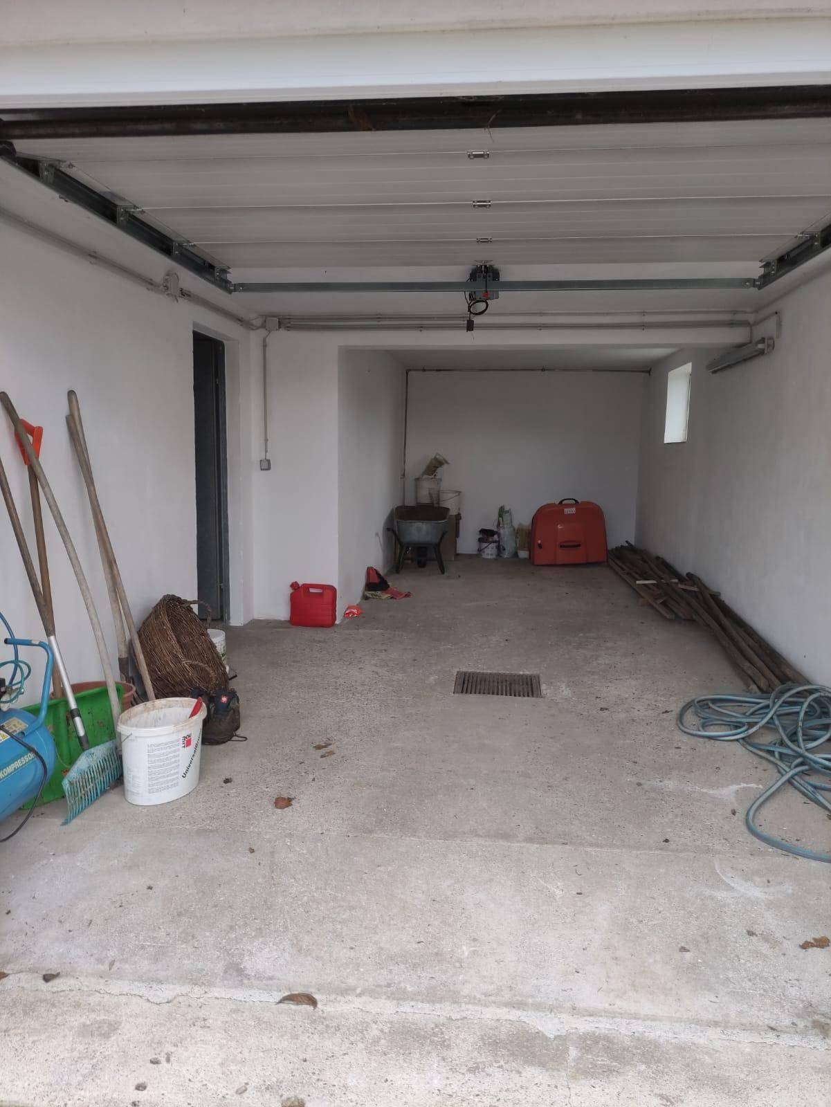 Innenansicht einer Garage mit Betonboden und Blick auf das Garagentor.