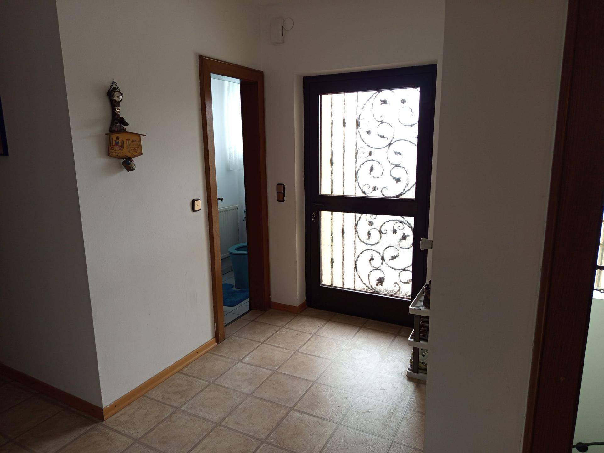 Eingangsbereich mit Fliesenboden und Blick auf eine Gästetoilette.
