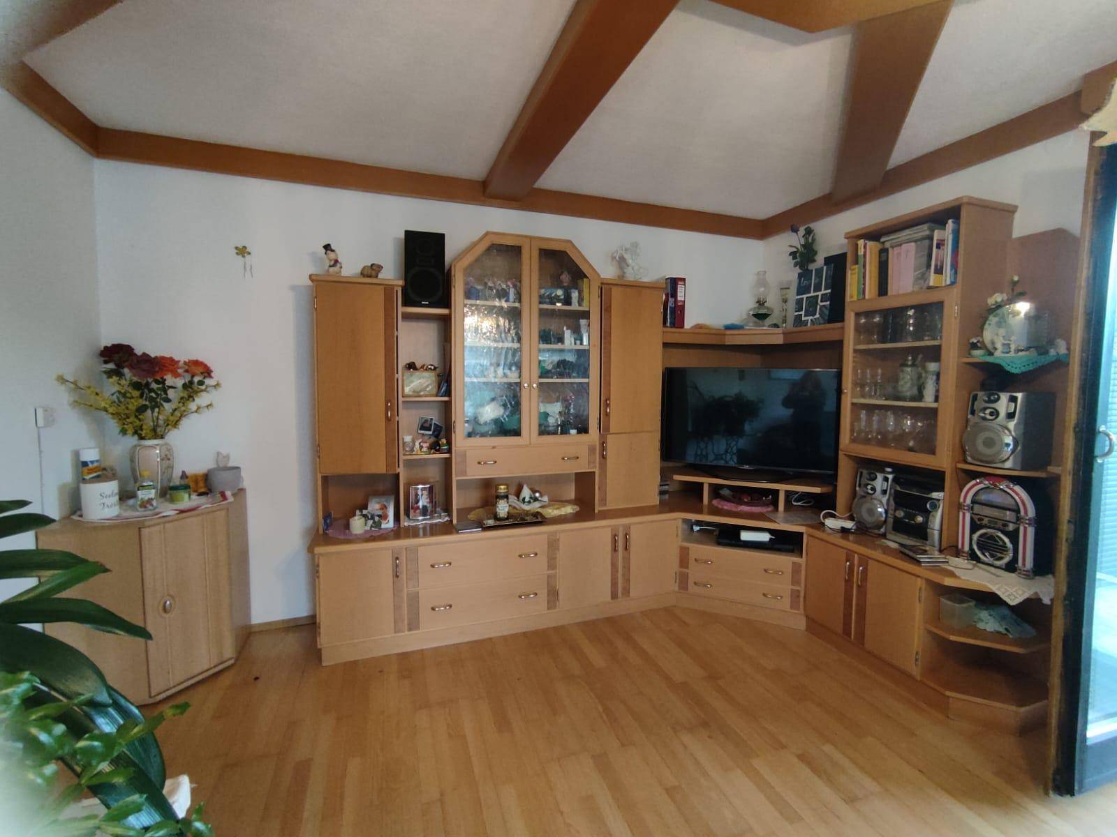Wohnzimmer mit großer Holzschrankwand, Parkettboden und traditioneller Einrichtung.
