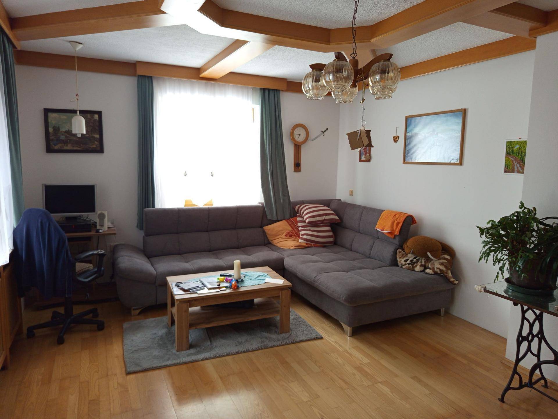 Wohnzimmer mit Holzbalkendecke, Parkettboden und großem Ecksofa.