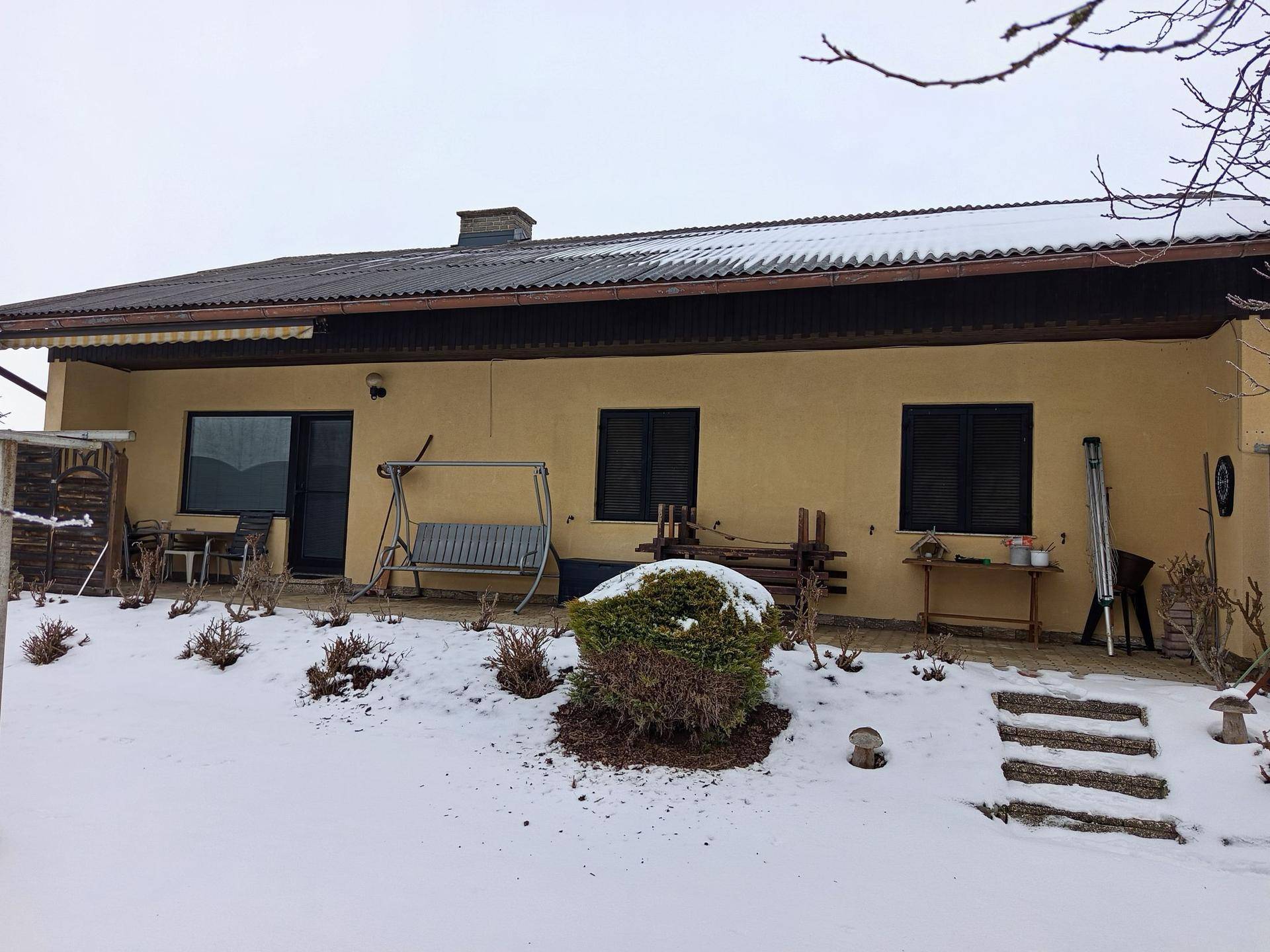 Rückseite des Hauses mit einer Terrasse und Gartenbereich, bedeckt mit Schnee.