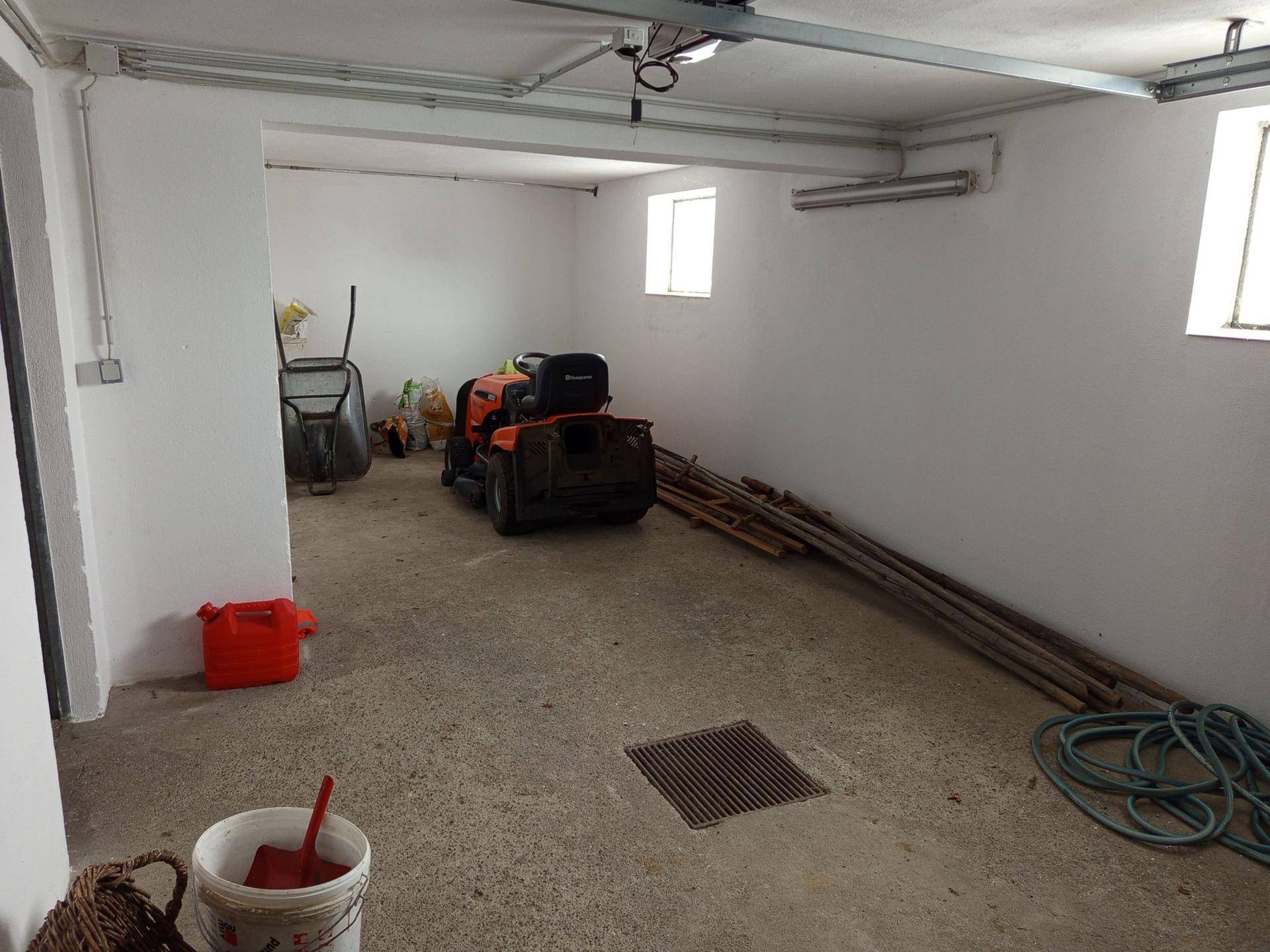 Geräumige Garage mit Betonboden und Fenstern, genutzt für Fahrzeuge und Lagerung.