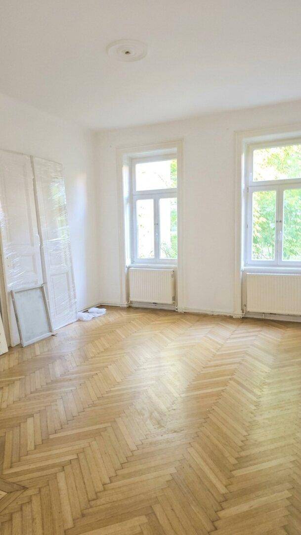 Geräumiger Raum mit Fischgrätparkett und zwei Fenstern, bereit für die individuelle Gestaltung.
