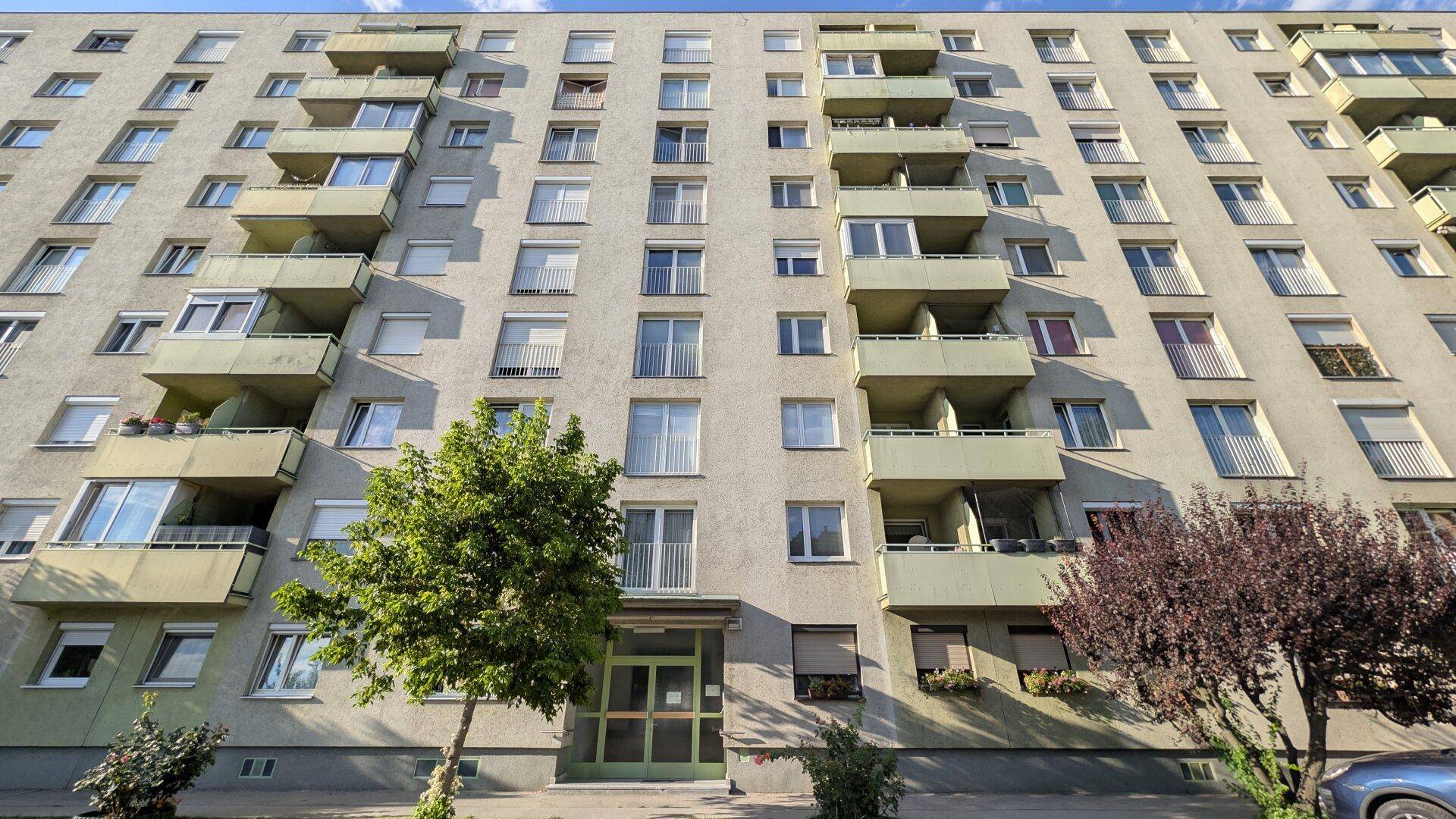 Mehrstöckiges Wohngebäude mit zahlreichen Balkonen und Fenstern in städtischer Umgebung.