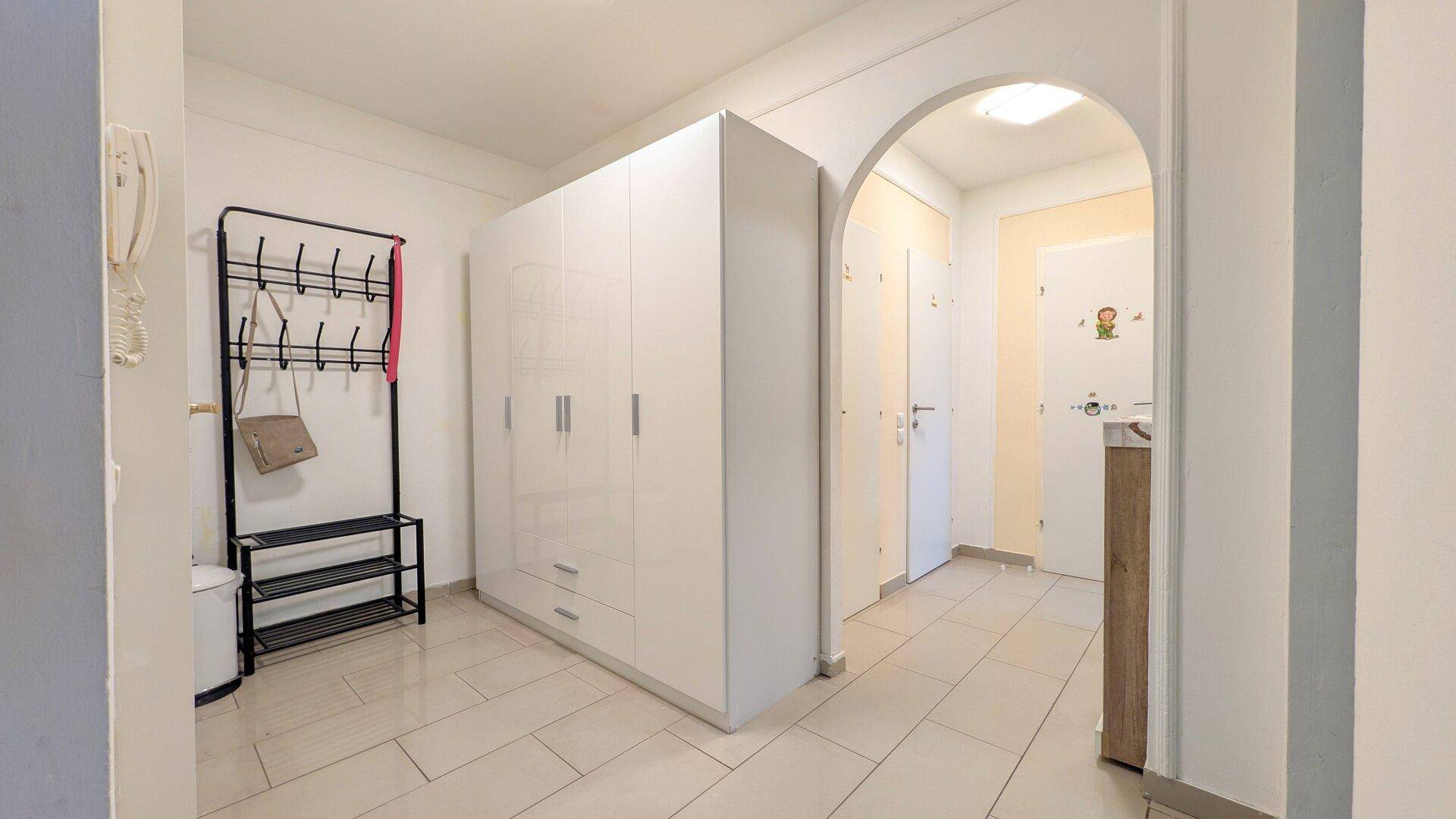 Geräumiger Flur mit hellen Fliesen, großem Garderobenschrank und praktischer Kleiderstange.
