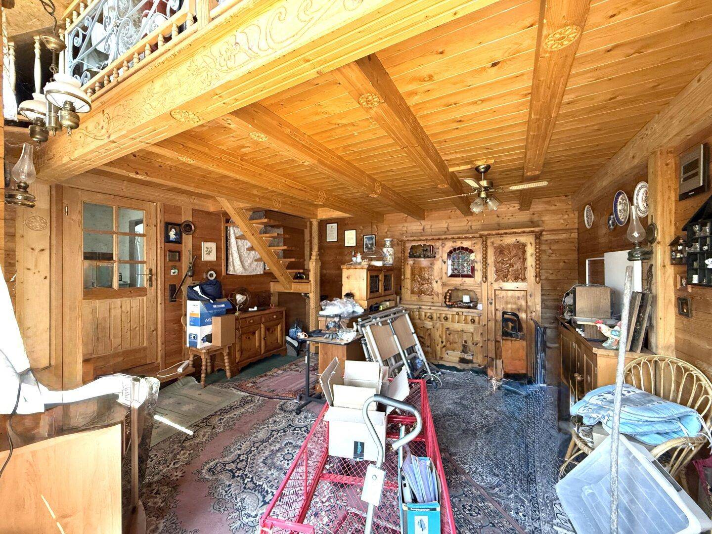 Rustikaler Wohnraum mit Holzbalkendecke, Holzvertäfelung und traditionellen Möbeln.