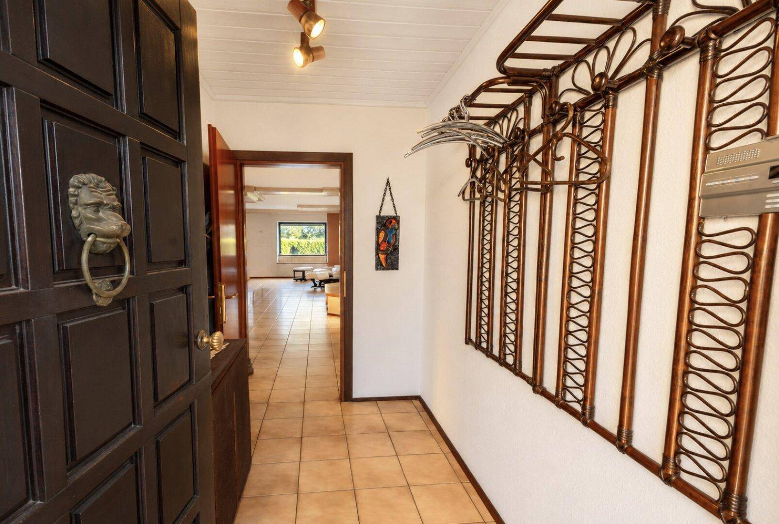 Eingangsbereich mit Fliesenboden, einer massiven Holztür und einer dekorativen Garderobe.
