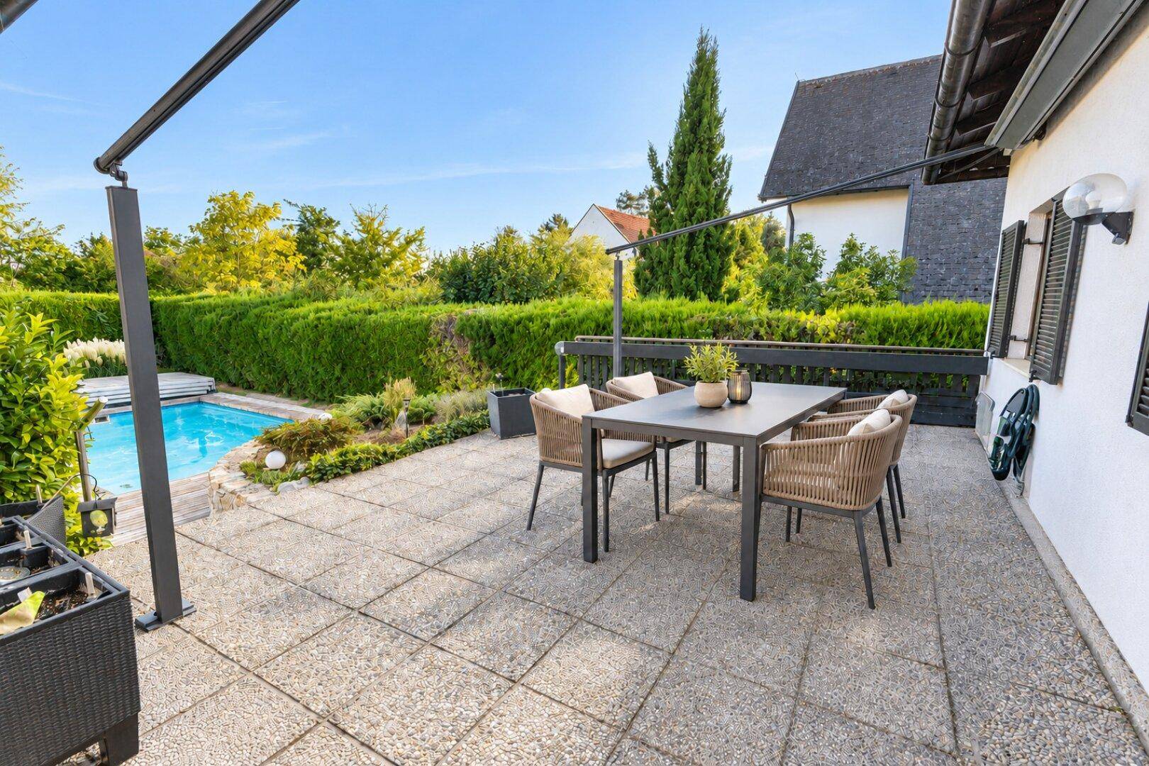 Geräumige Terrasse mit modernen Gartenmöbeln, ideal für Entspannung am Pool und im Grünen.