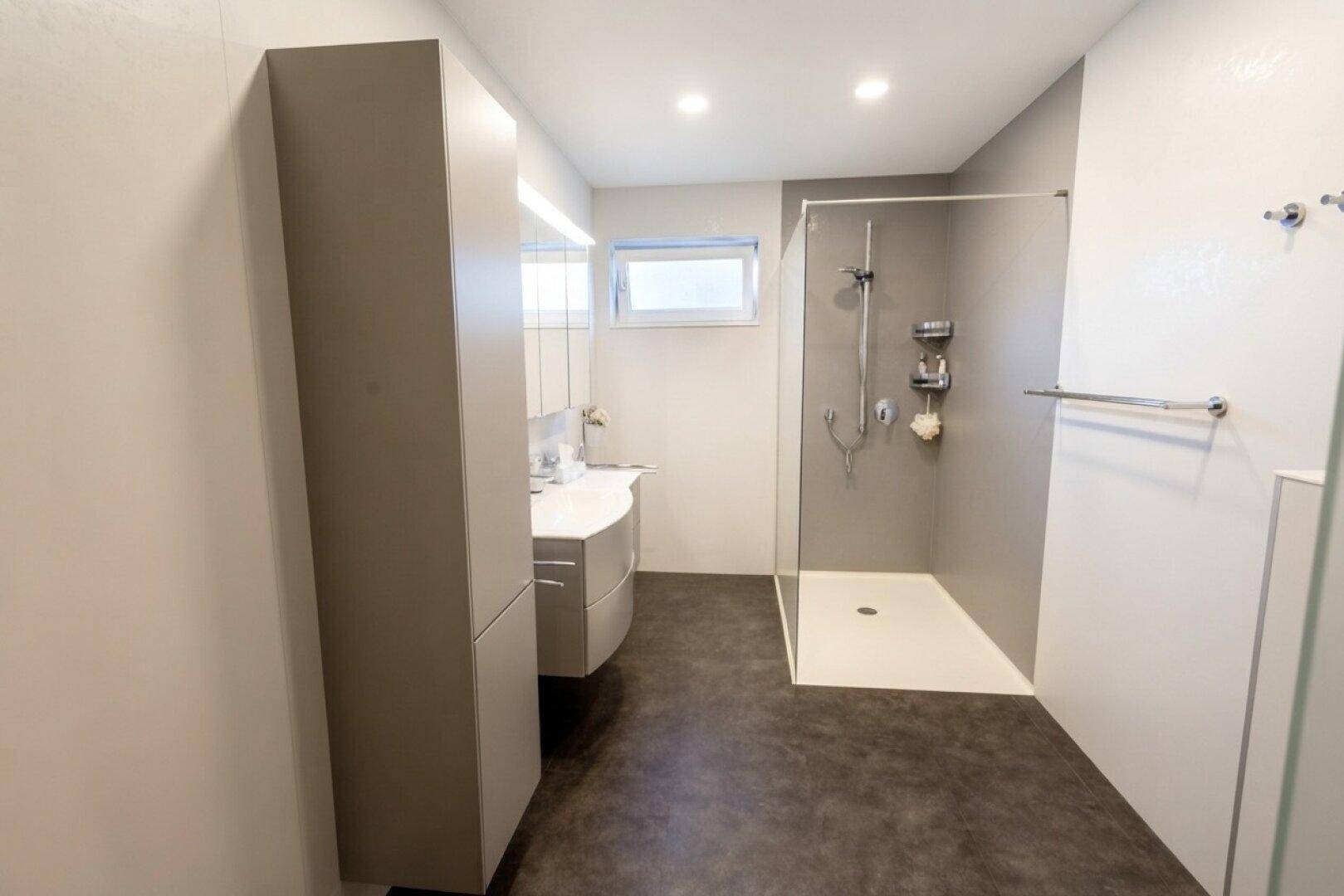 Modernes Badezimmer mit ebenerdiger Dusche, Einzelwaschbecken und Fenster für Tageslicht.