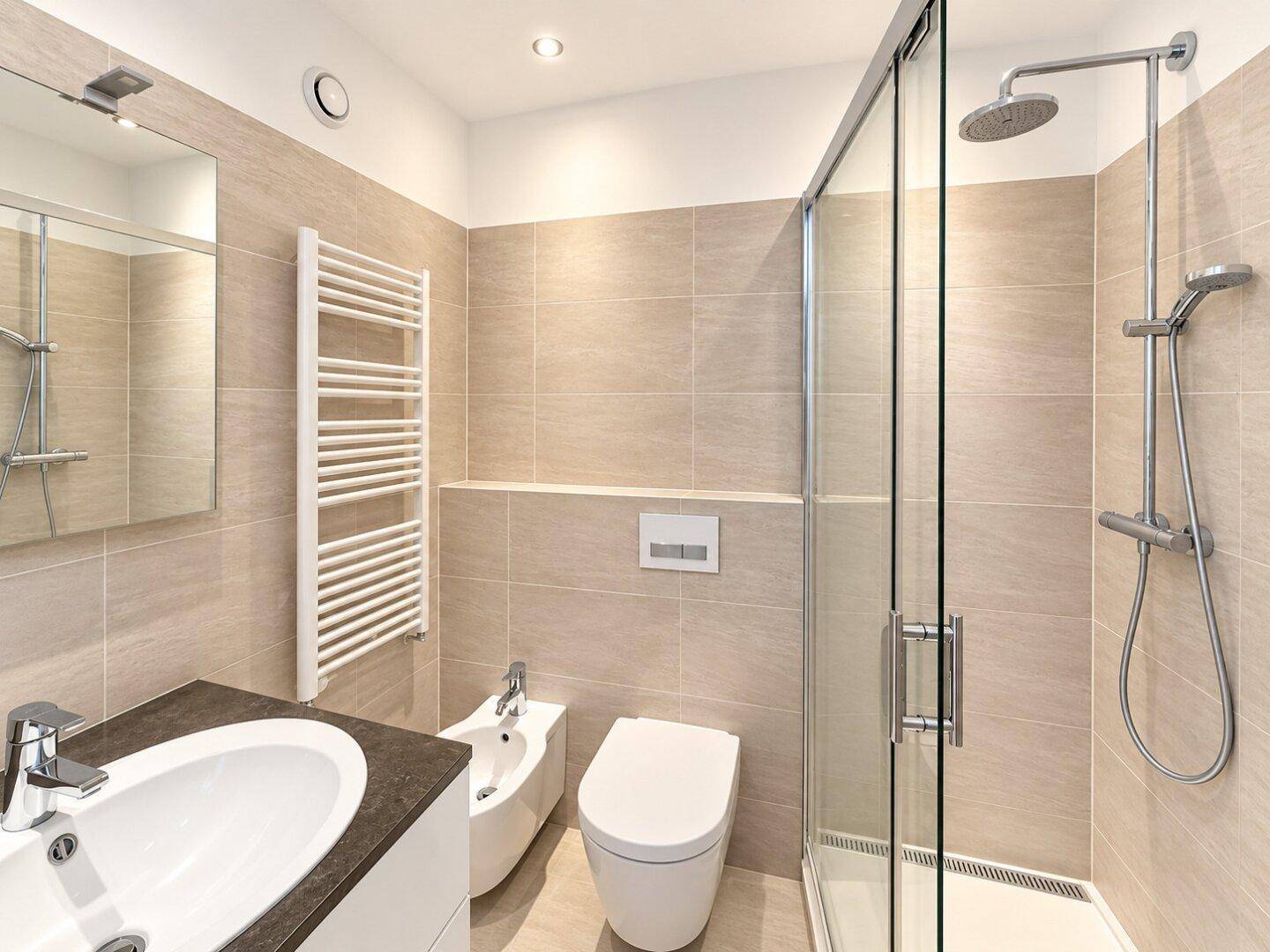 Modernes Badezimmer mit begehbarer Dusche, WC, Bidet und beheiztem Handtuchhalter.