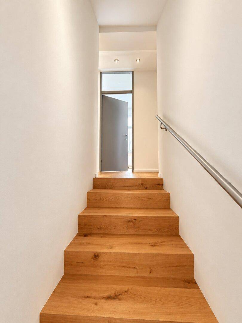 Elegante Holztreppe mit modernem Geländer, die in die obere Etage führt.