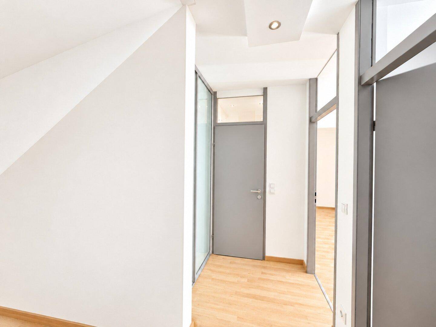 Heller Flur mit Holzboden und modernen Türen, die zu den verschiedenen Räumen führen.