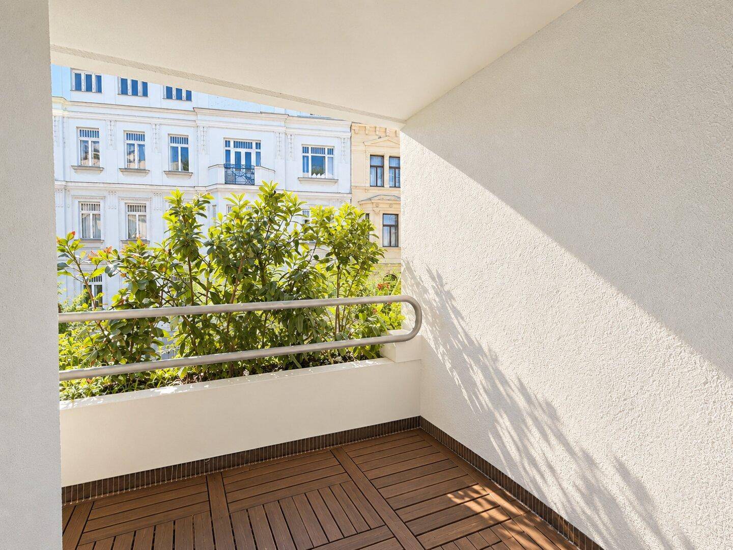 Geräumiger Balkon mit Holzdielen und Blick auf die umliegenden Gebäude.