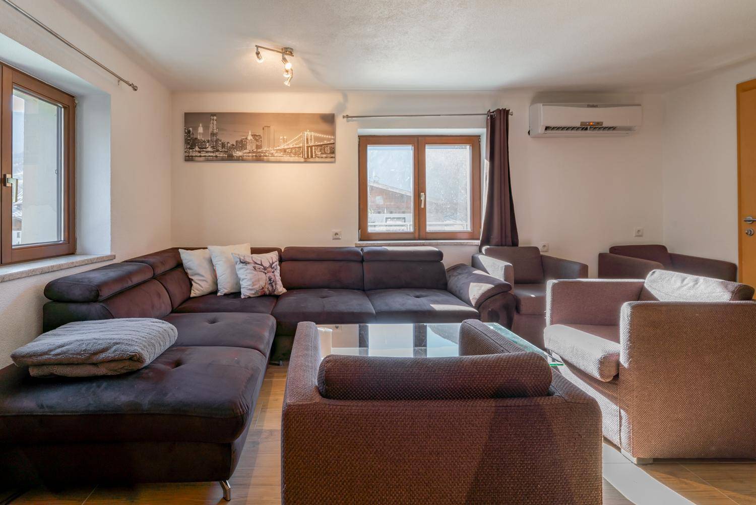 Geräumiges Wohnzimmer mit großem Ecksofa, Couchtisch und Klimaanlage, ideal zum Entspannen.