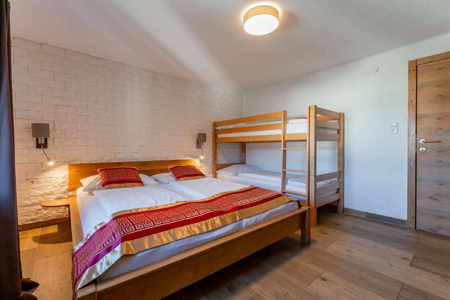 Gemütliches Schlafzimmer mit Doppelbett, Etagenbett und Holzboden, ideal für Familien.