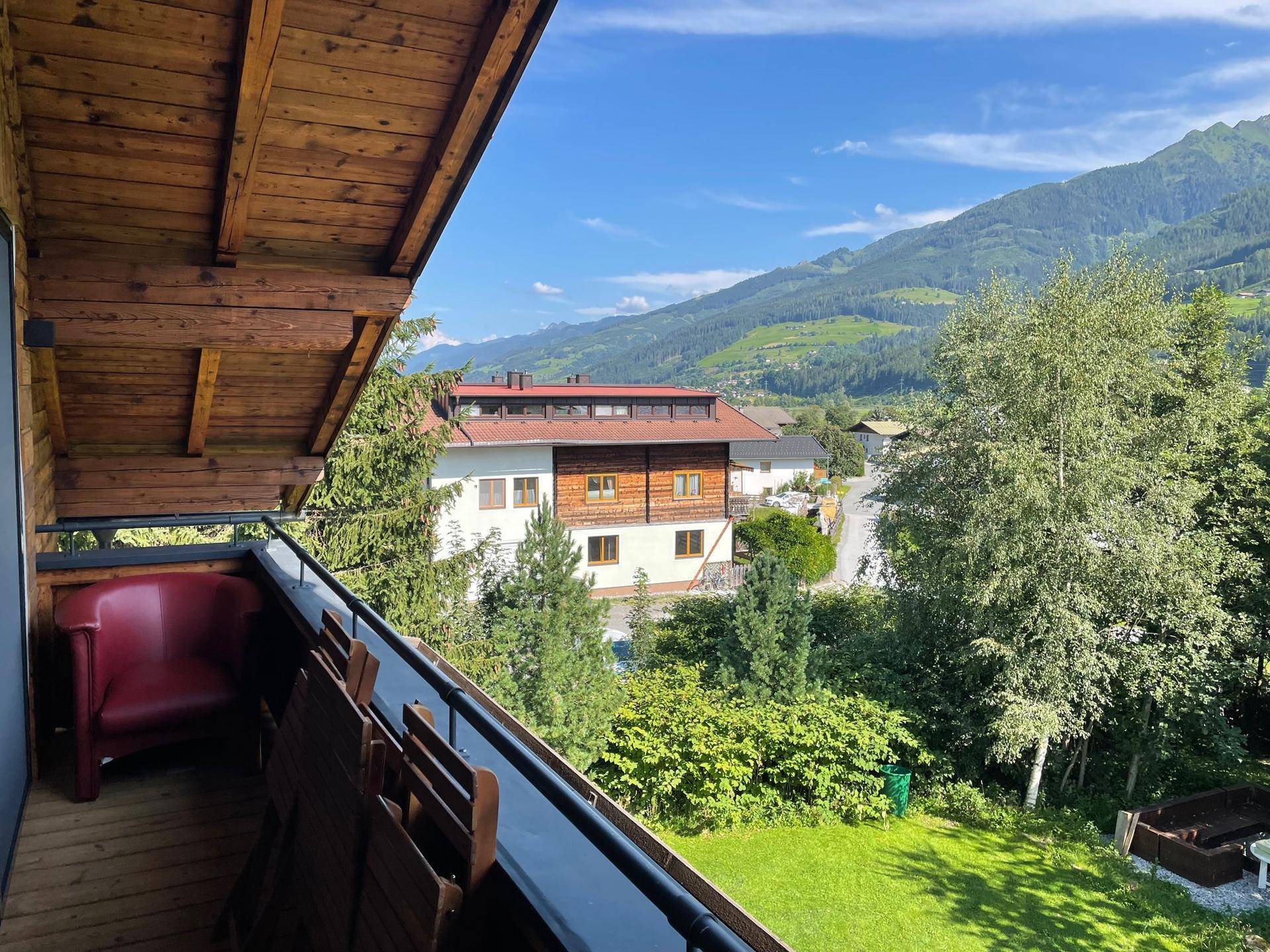 Geräumiger Balkon mit Holzboden und Blick auf die grüne Umgebung und die Berge.