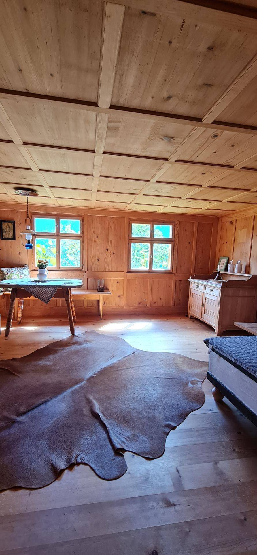 Gemütliches Wohnzimmer mit Holztäfelung, Kassettendecke und traditionellen Möbeln.