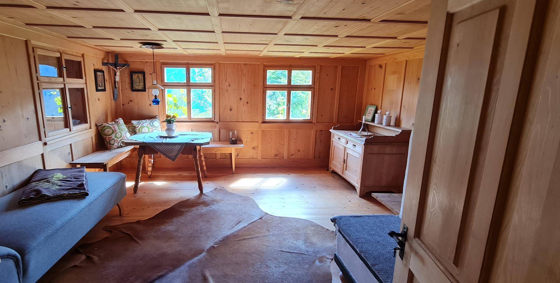 Helles Wohnzimmer mit Holzboden, Kassettendecke und rustikalen Möbeln, ideal zum Entspannen.