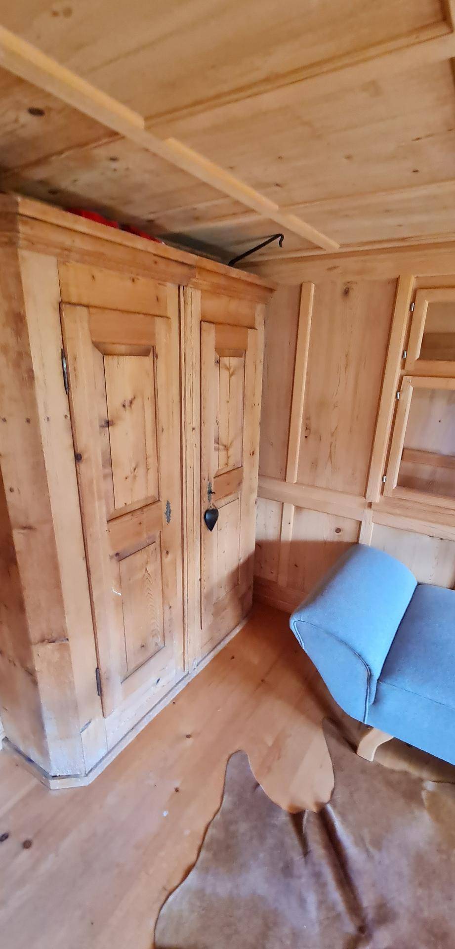 Detailansicht eines traditionellen Holzschranks im rustikalen Wohnzimmer mit Holzboden.