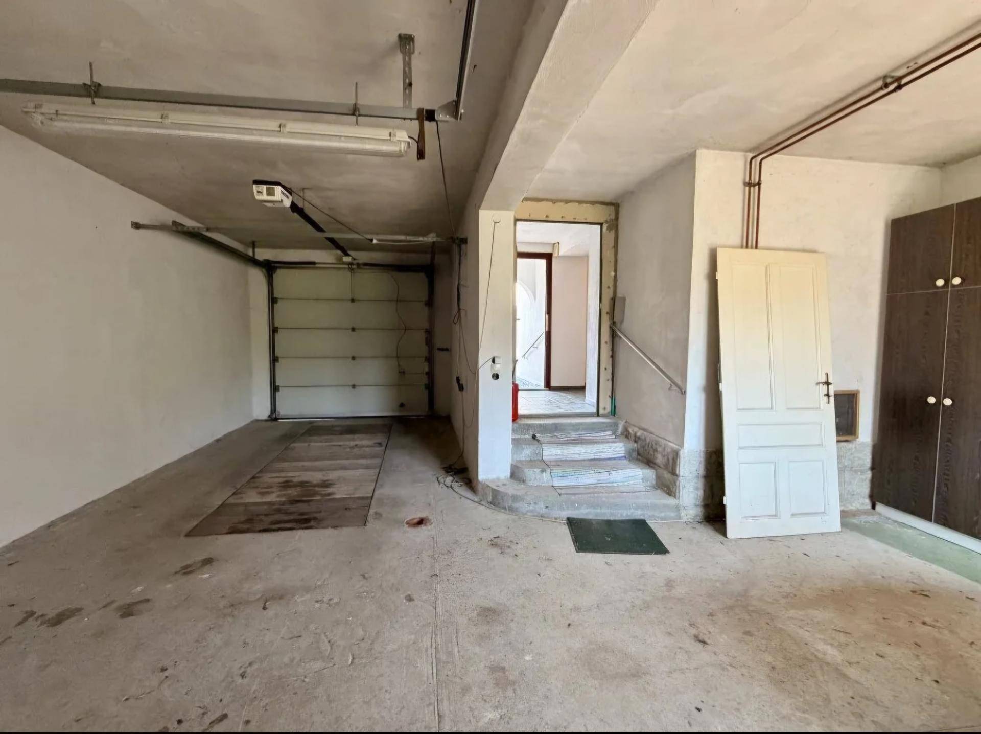 Geräumige Garage mit Rolltor, Betonboden und direktem Zugang zum Haus.