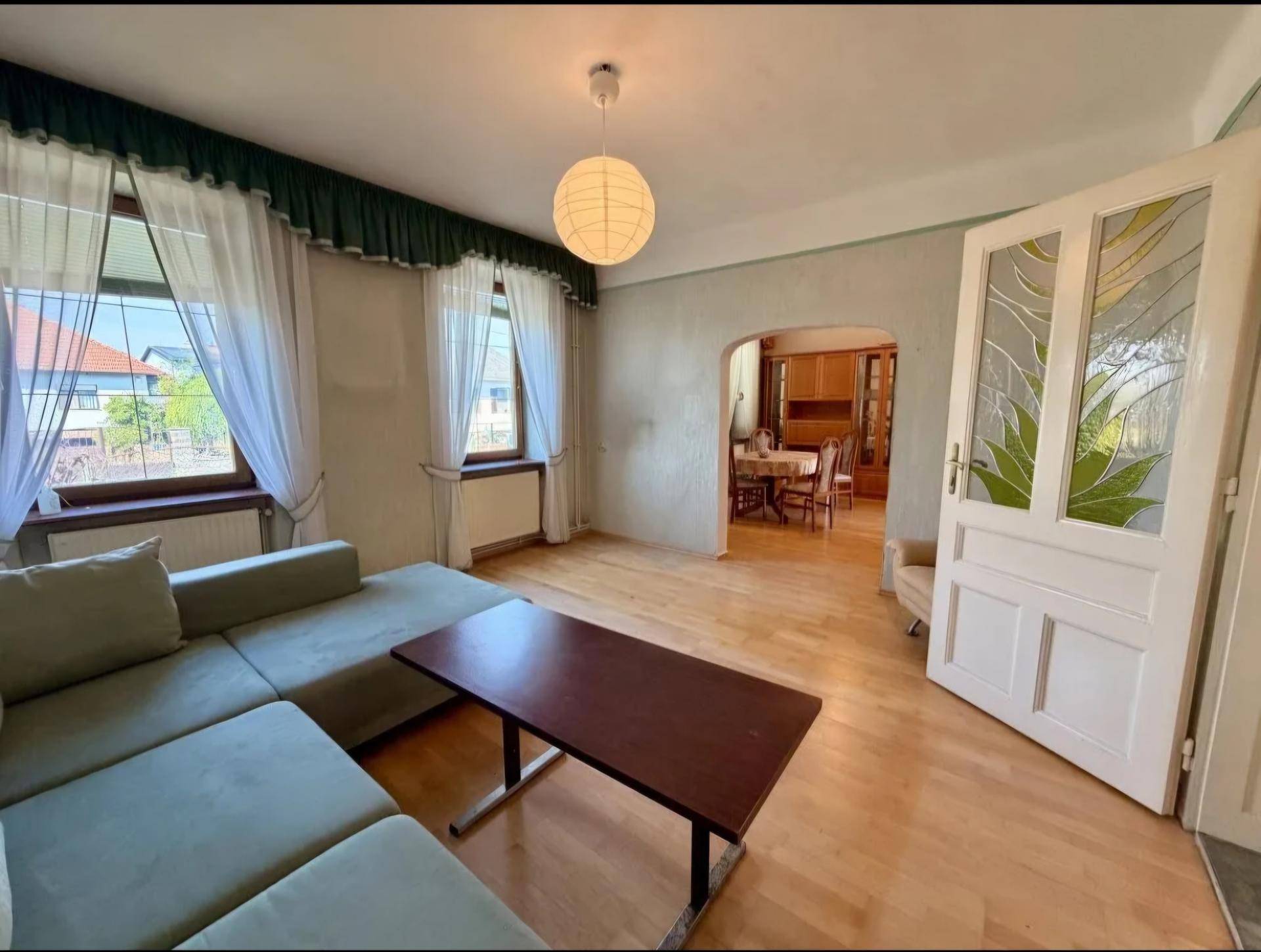 Gemütliches Wohnzimmer mit Sofa, Holzboden und Zugang zum angrenzenden Essbereich.