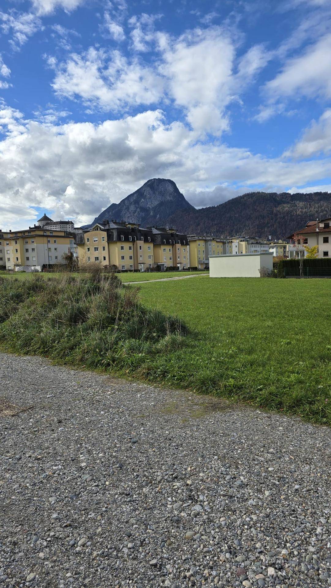 Weitläufiges grünes Grundstück mit Blick auf die umliegende Berglandschaft und Wohngebäude.