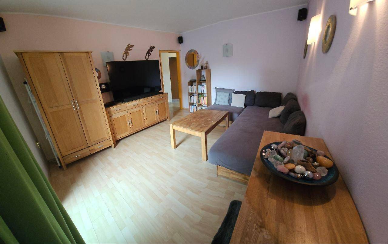 Geräumiges Wohnzimmer mit Ecksofa, Holzmöbeln und einem Fernseher, hell und freundlich.